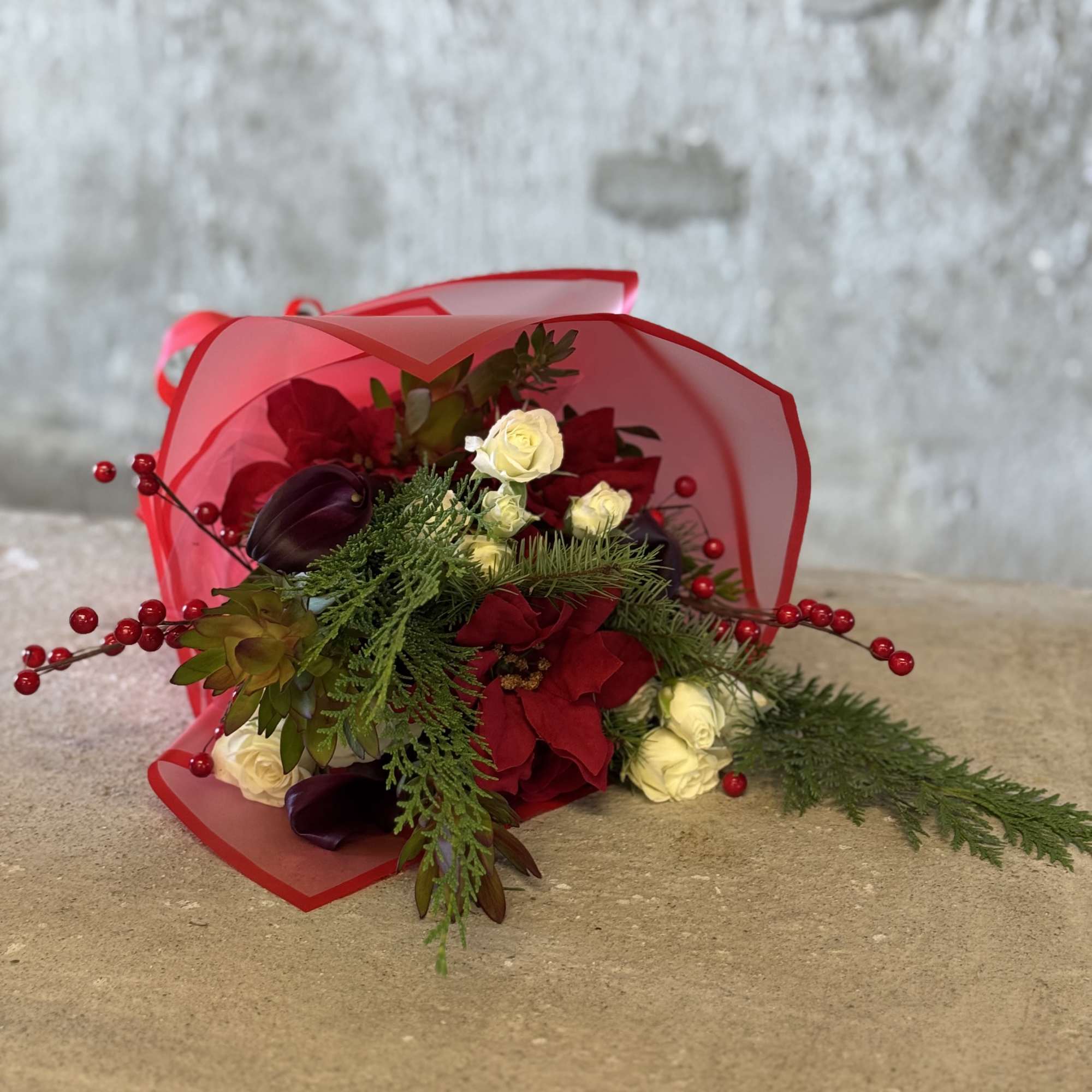 Bouquet of red and white roses with greenery and red berry accents