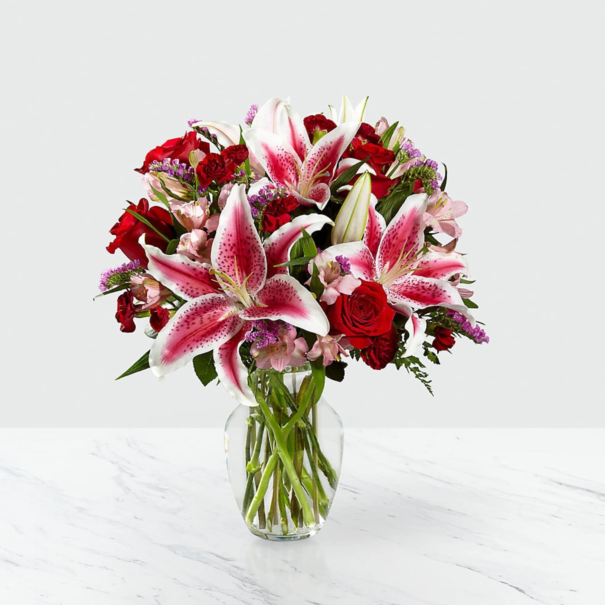 Bouquet of pink lilies and red roses in a clear glass vase