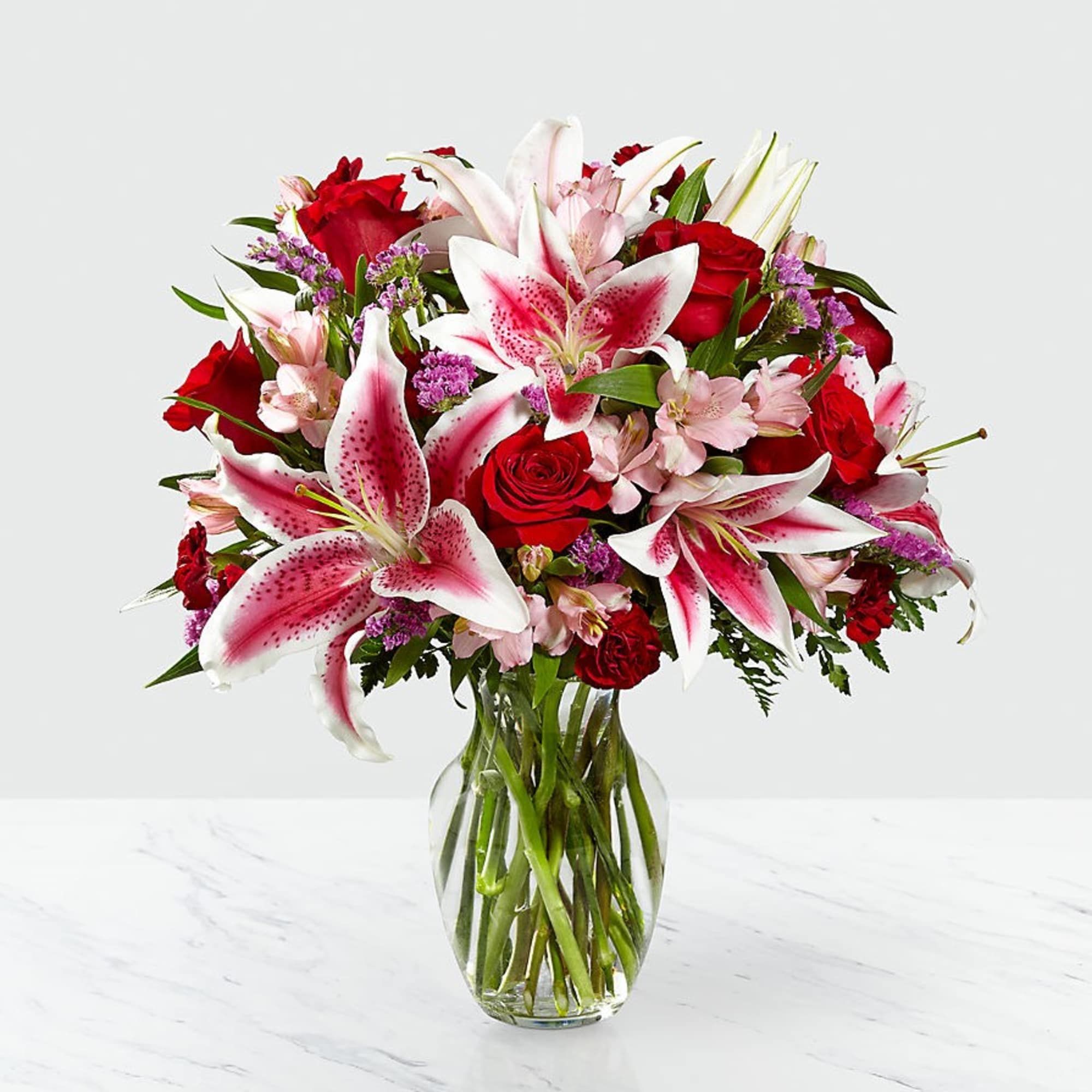 Bouquet of red roses and pink lilies in a clear glass vase