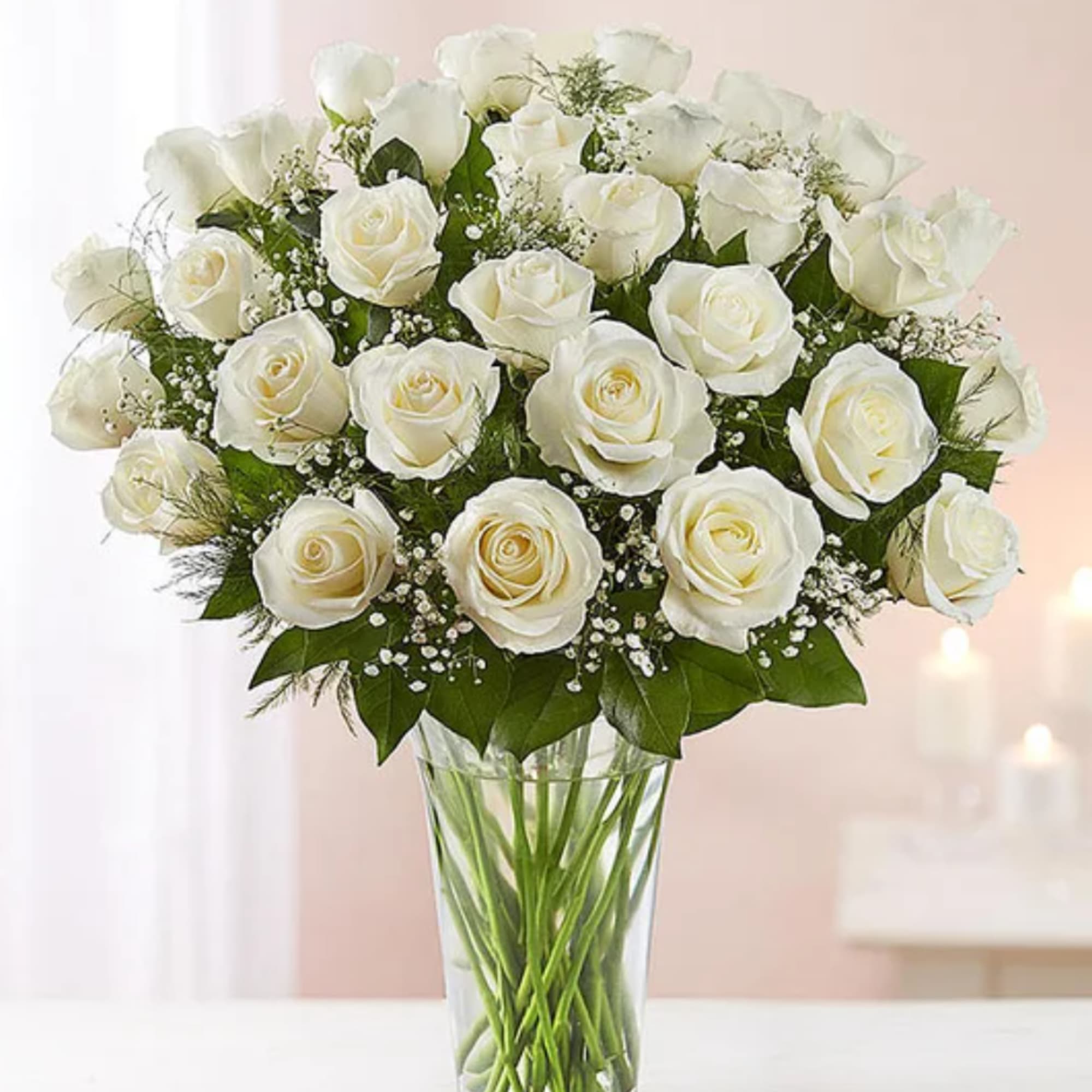 White roses arranged in a clear glass vase with baby's breath