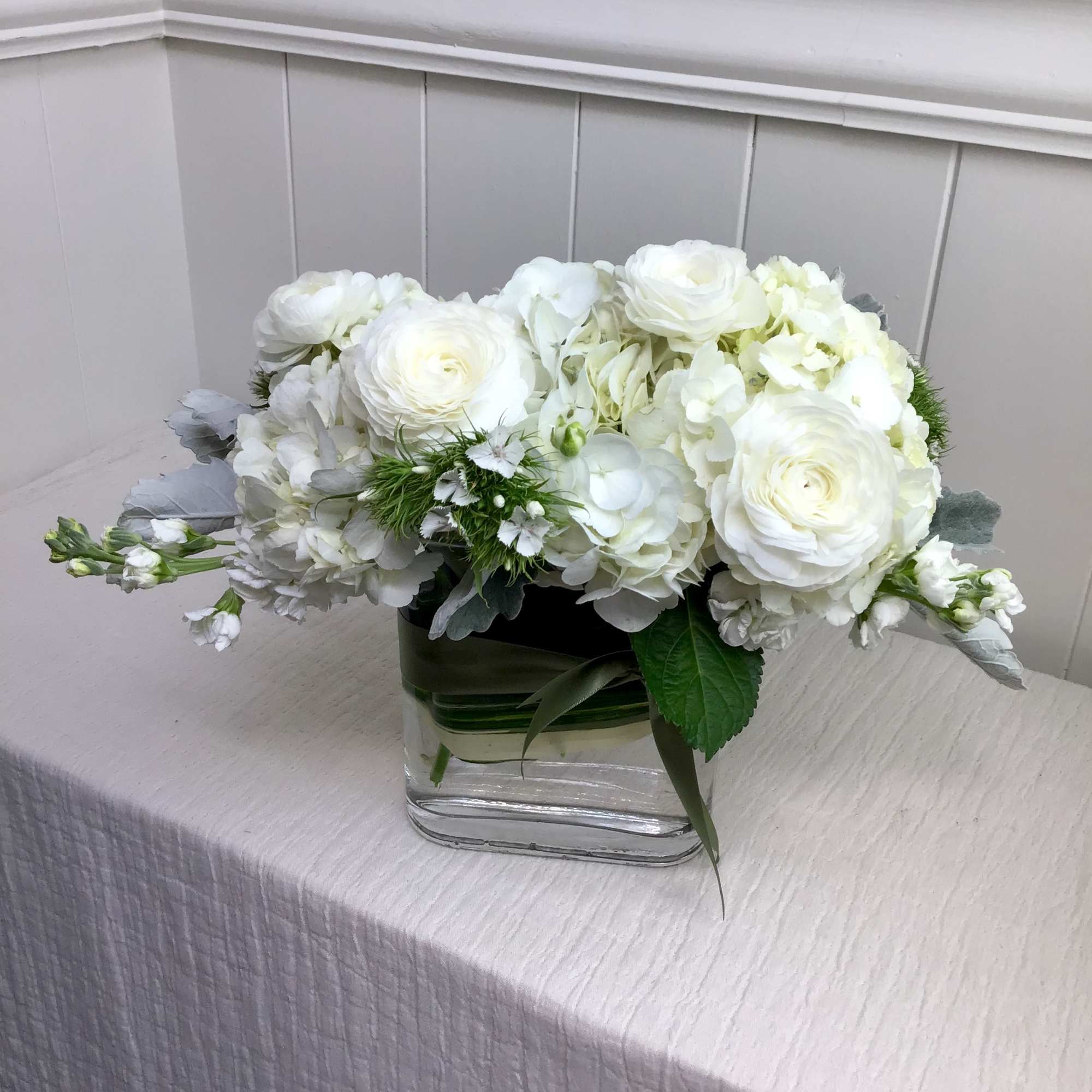 White floral arrangement in a clear square vase
