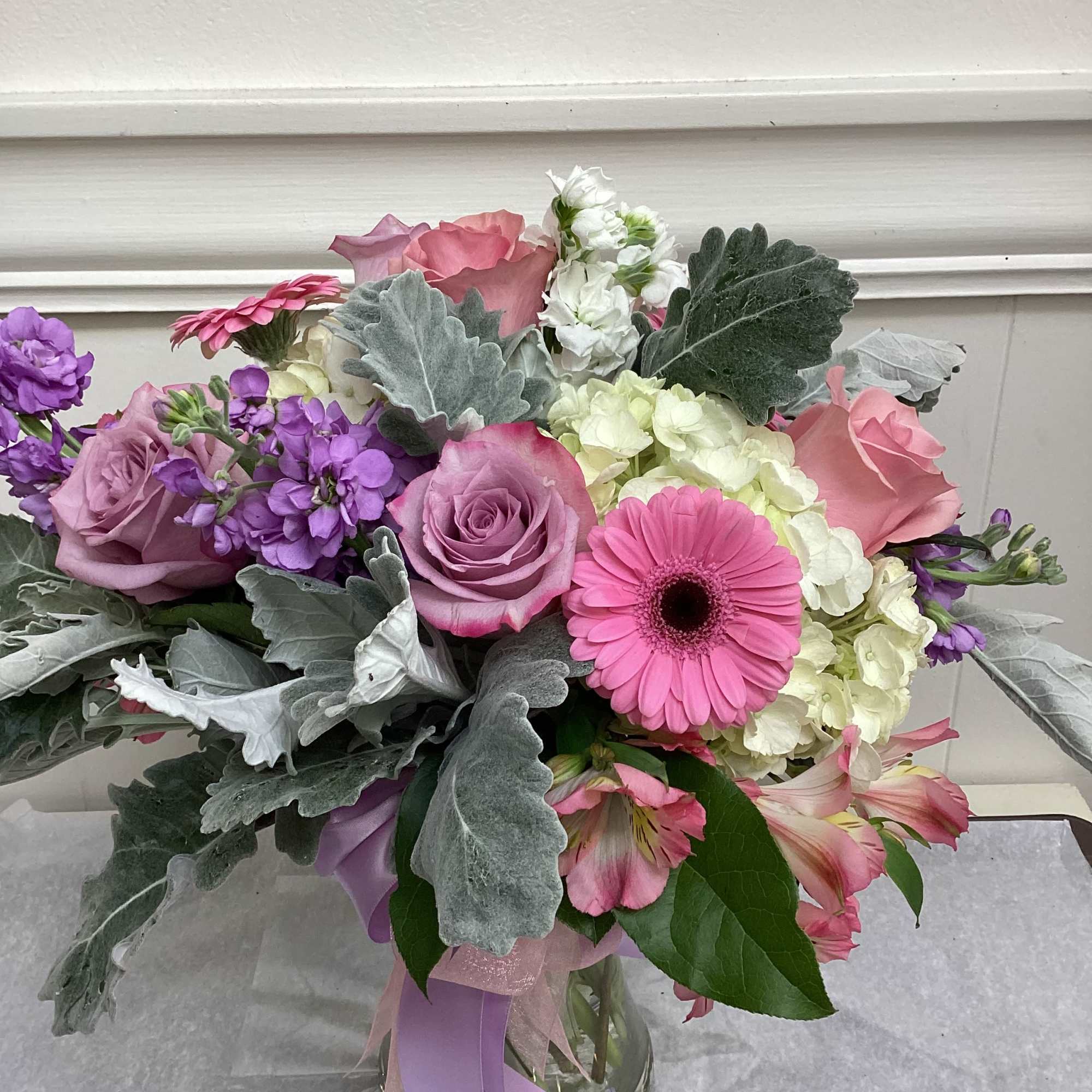 Beautiful pastel blooms in a clear or pink vase.  Includes roses