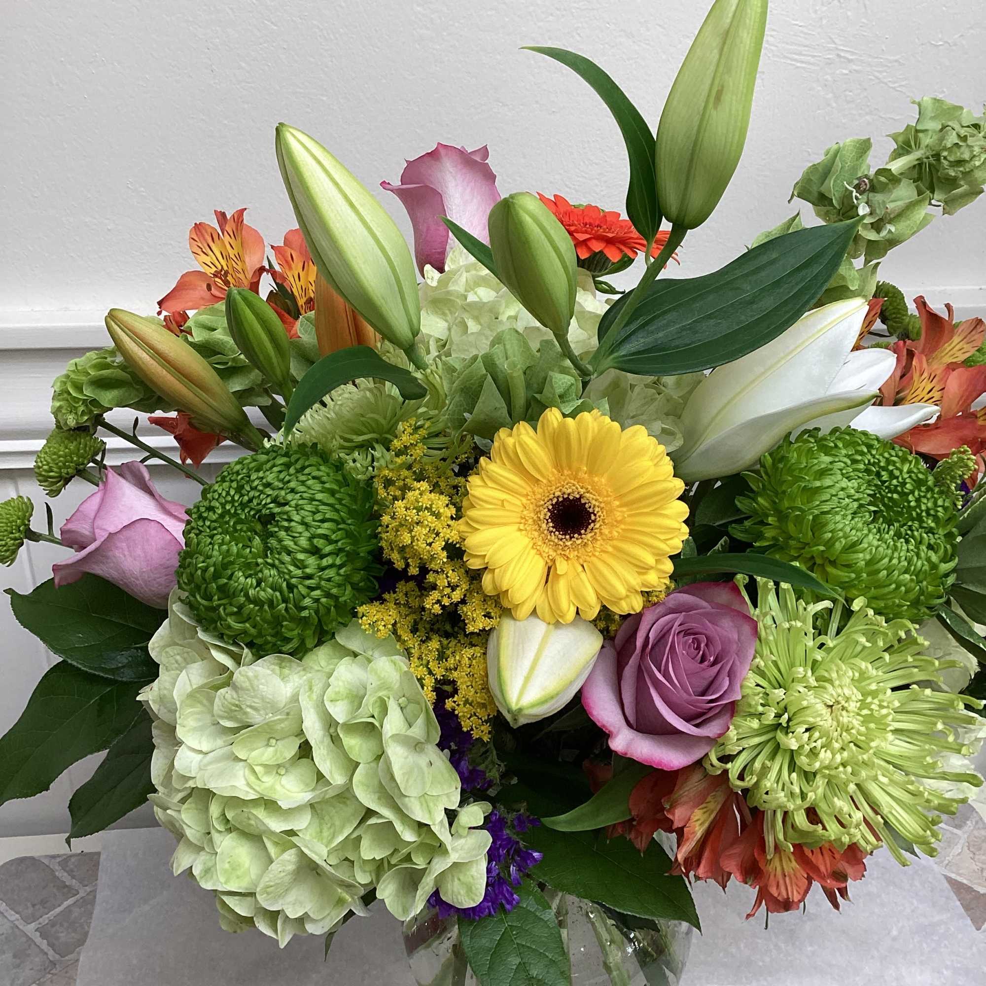 Mixed bouquet in a glass vase with lilies, roses, hydrangea, and chrysanthemums