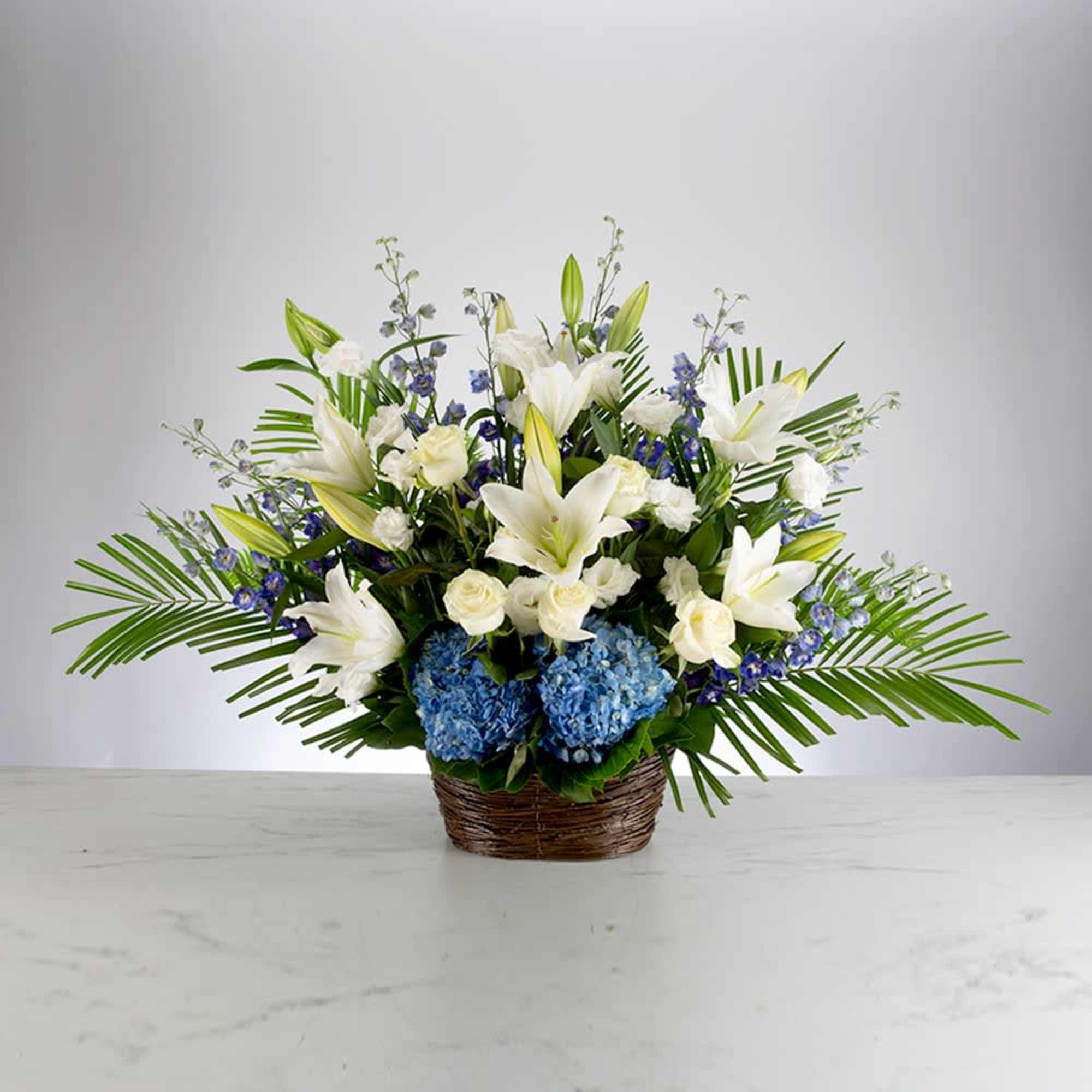 White lilies and blue hydrangeas in a woven basket