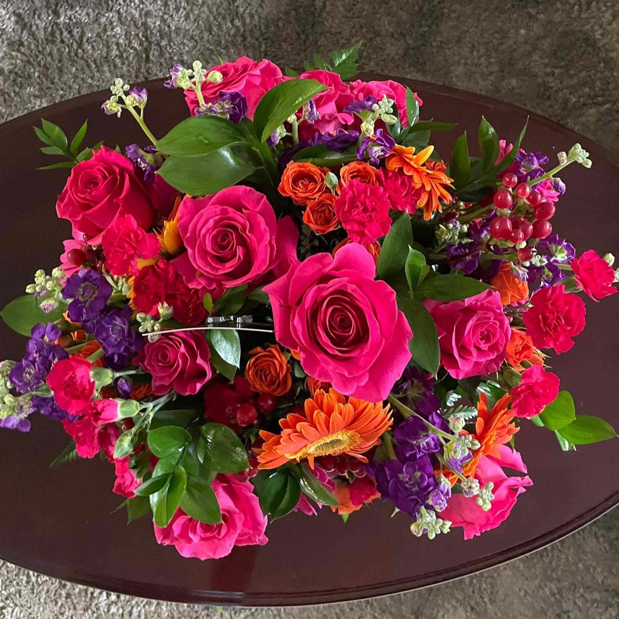 Bright mixed bouquet with pink roses and orange flowers on a dark table