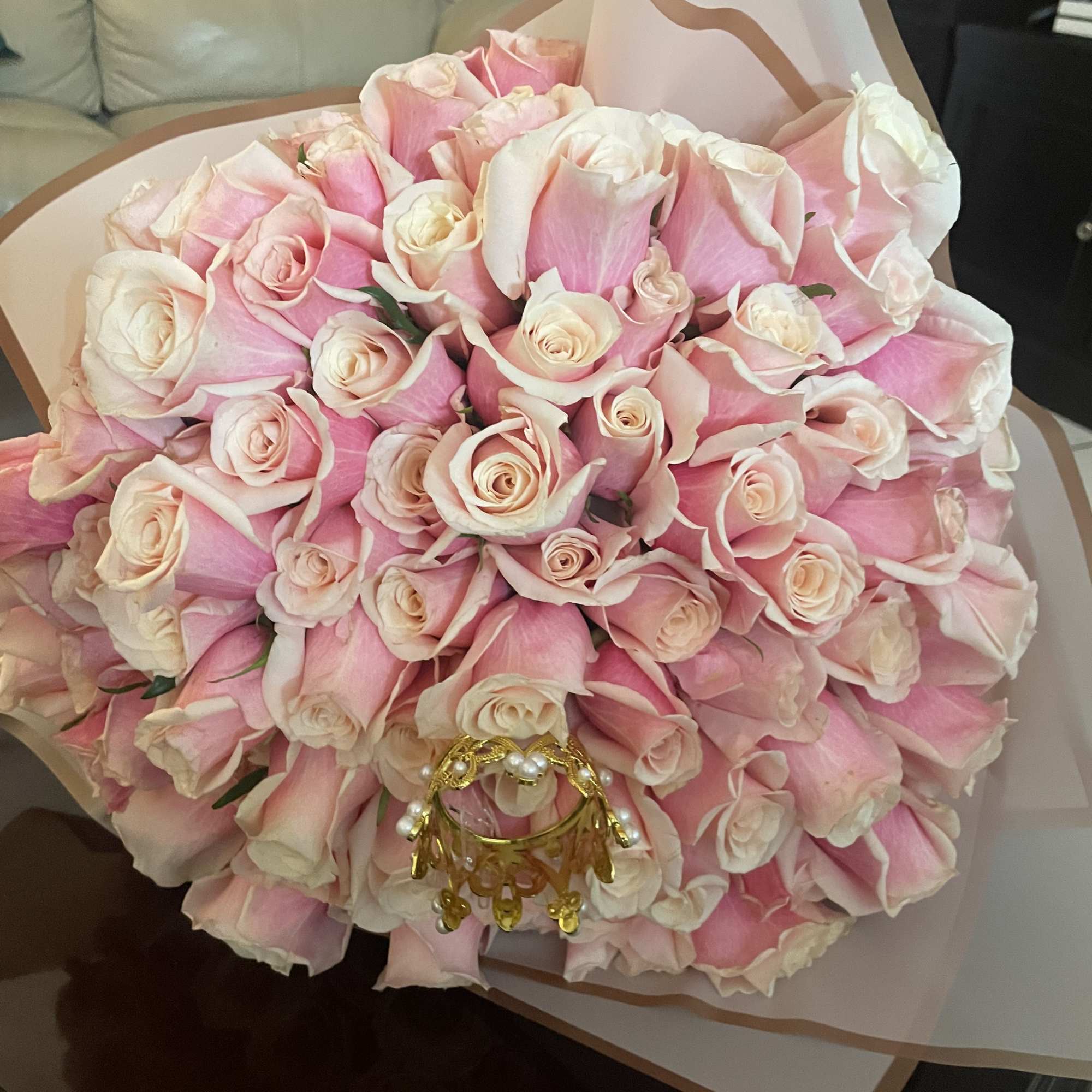 Large bouquet of pink and white roses wrapped in pale paper