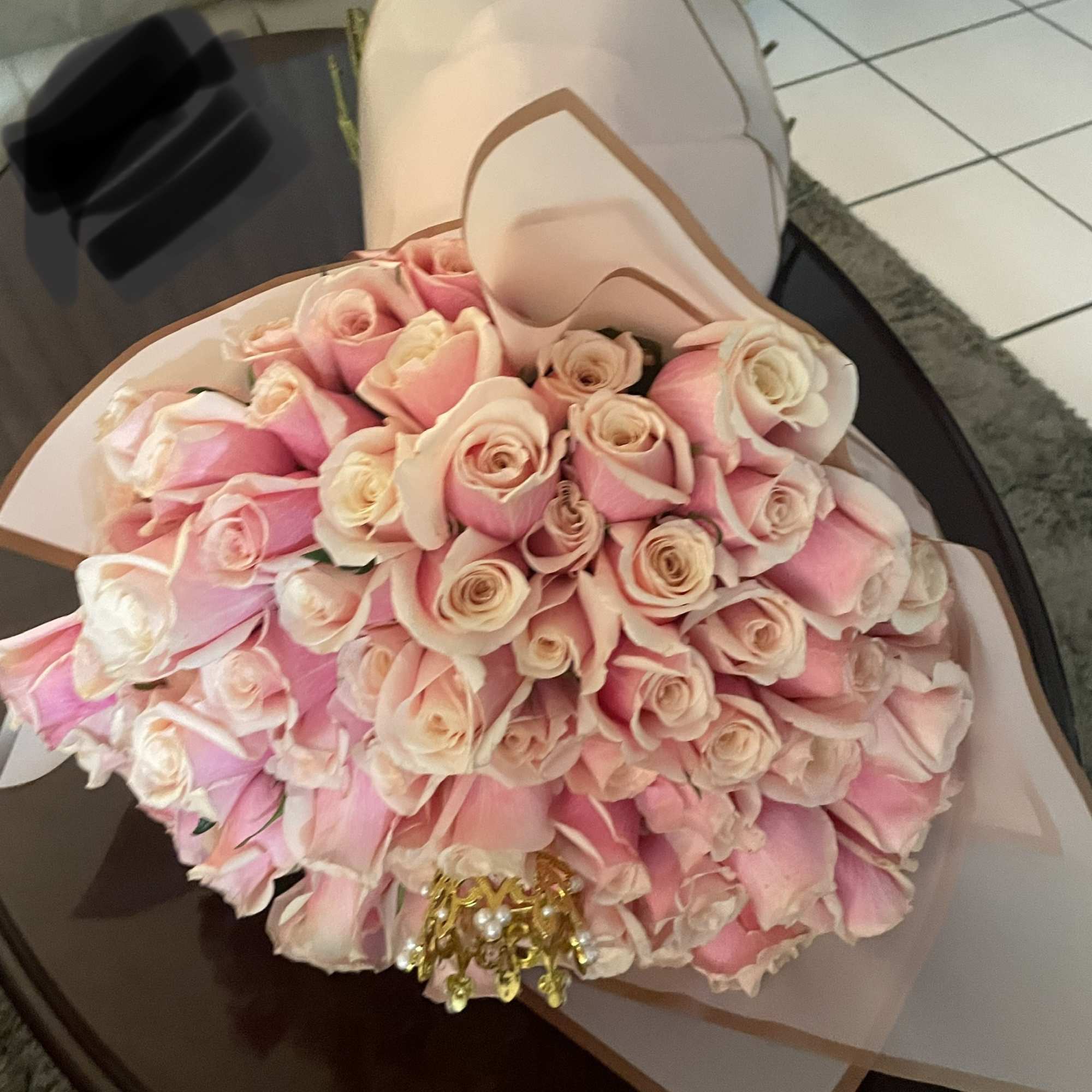 Bouquet of pink and cream roses wrapped in pale paper