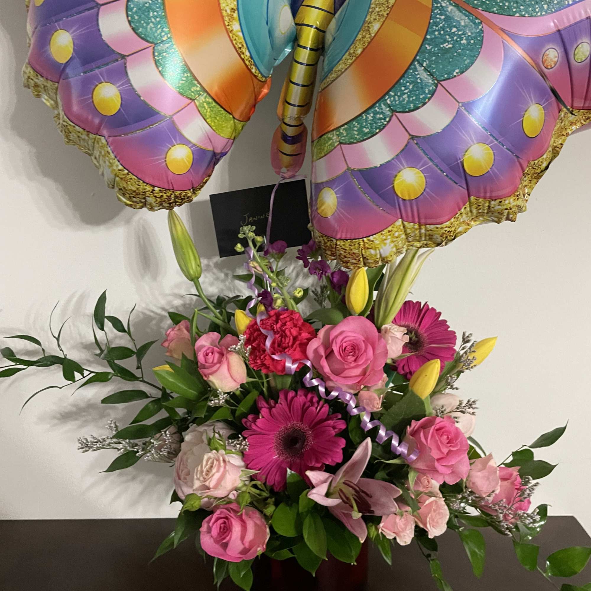 Pink floral arrangement with a colorful butterfly balloon