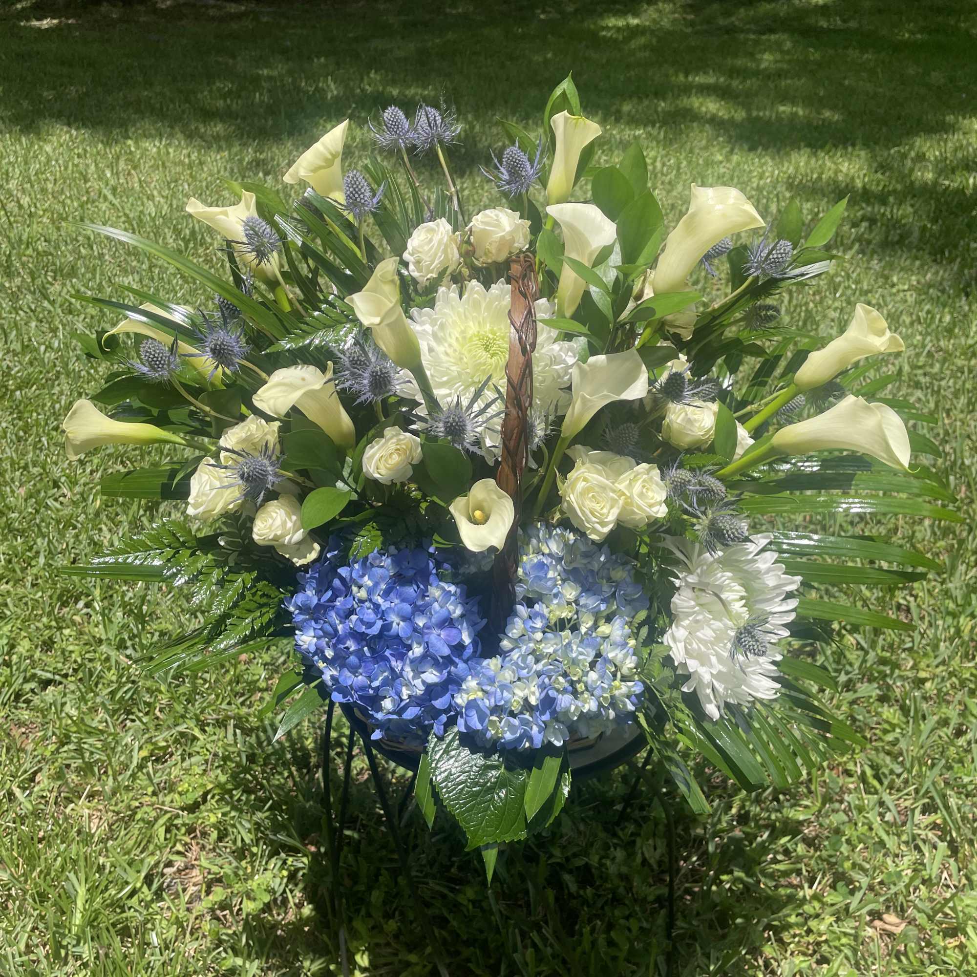 Large floral arrangement with white calla lilies, blue hydrangeas, and white roses