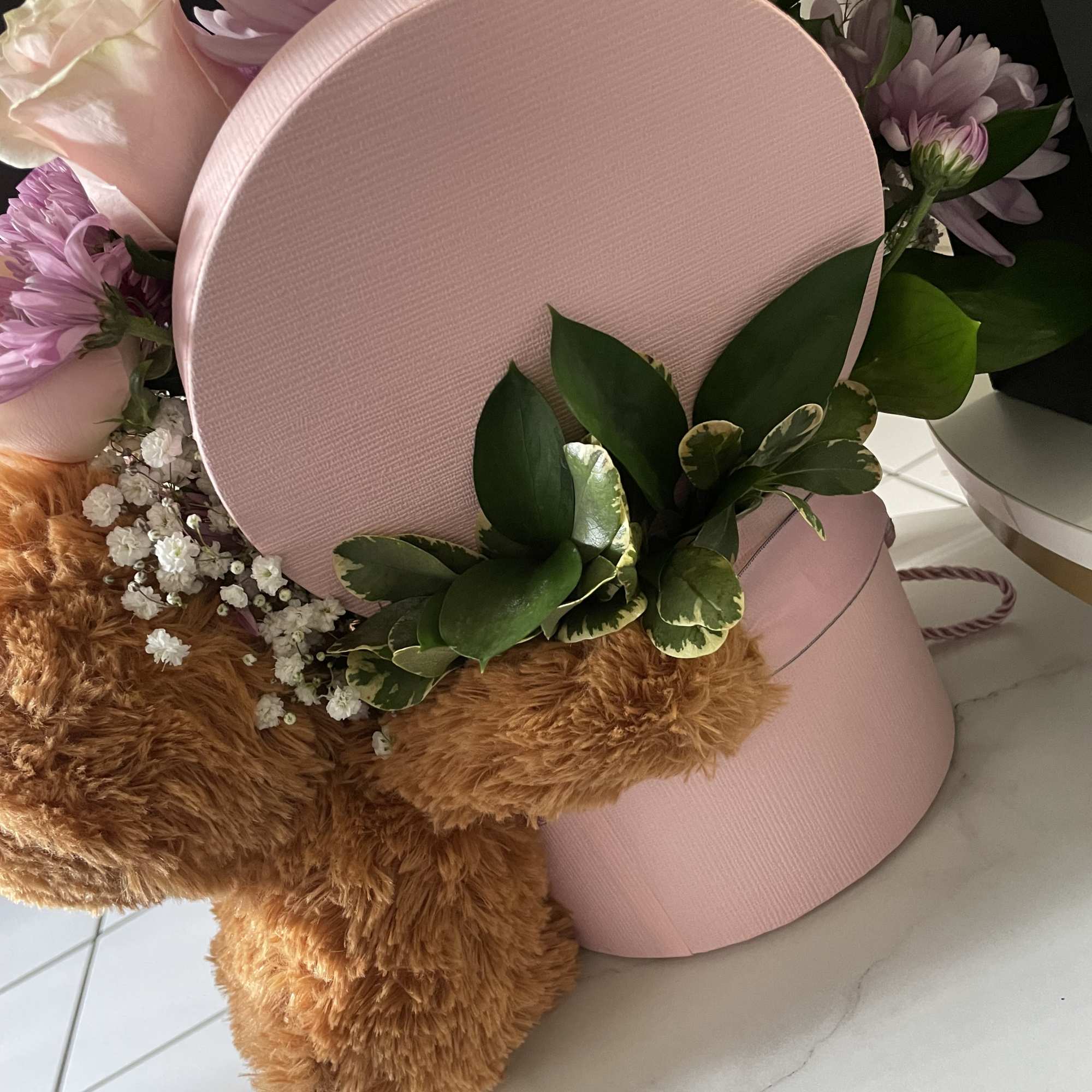 Pink hatbox arrangement with lavender flowers and a teddy bear