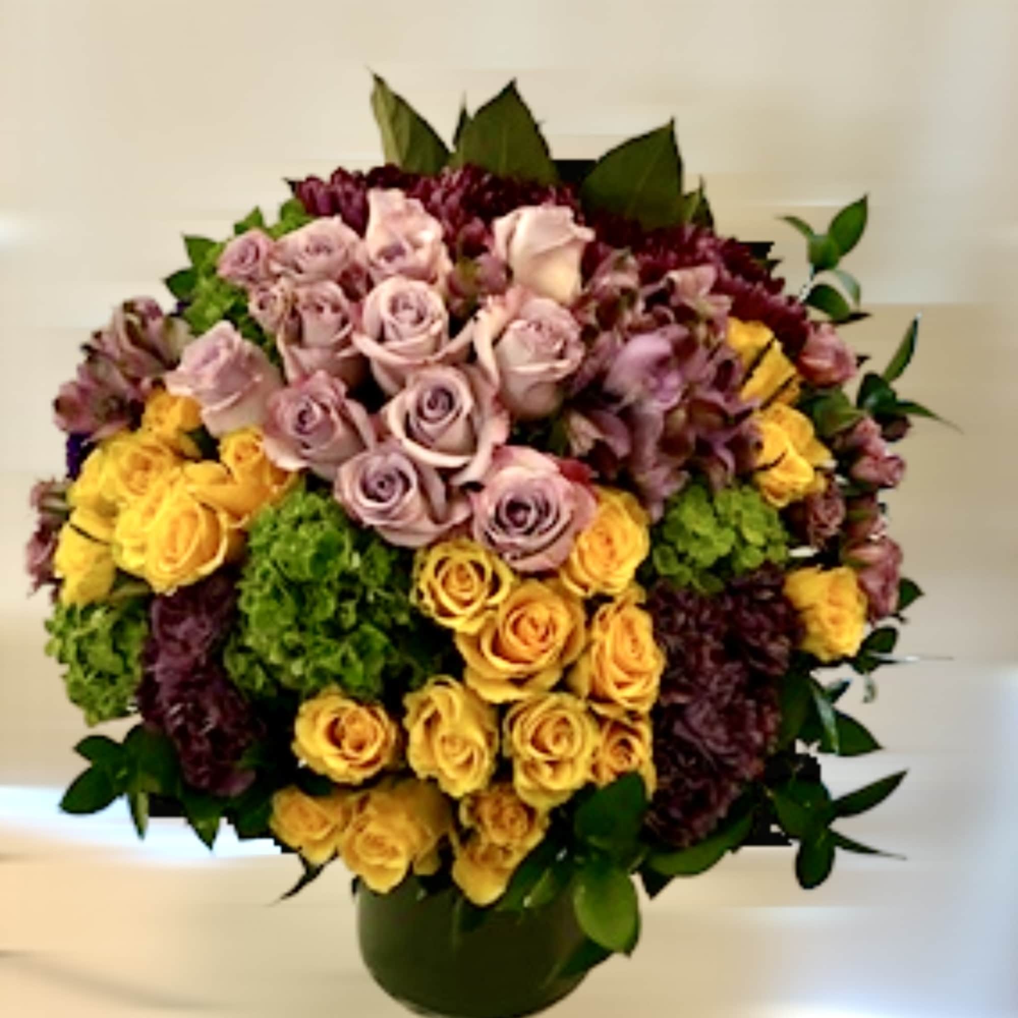 Bouquet of pink, yellow, and purple roses in a dark vase