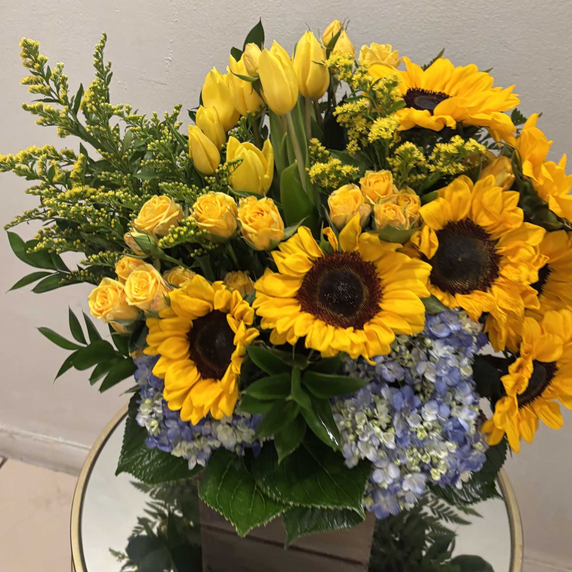 Bouquet of yellow sunflowers, tulips, roses, and blue hydrangeas