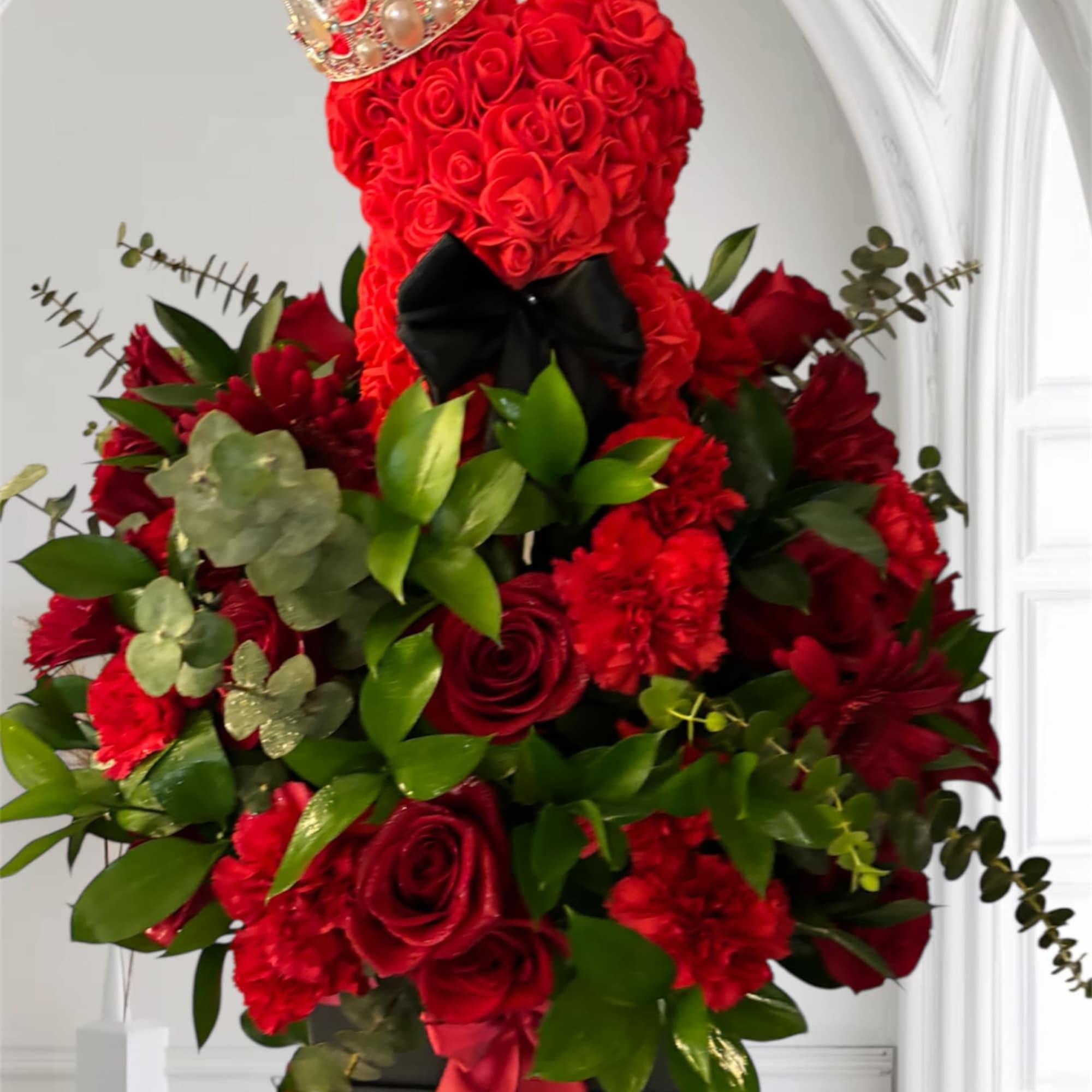 Red rose teddy bear arrangement with a crown and black bow