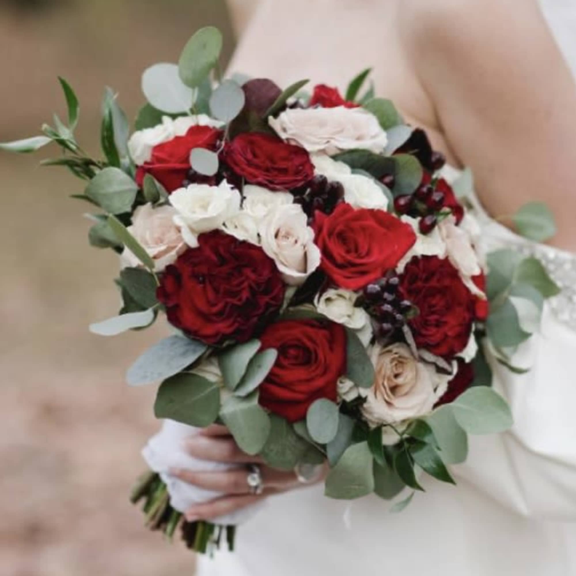 Bride holding a bouquet of red and white roses with eucalyptus