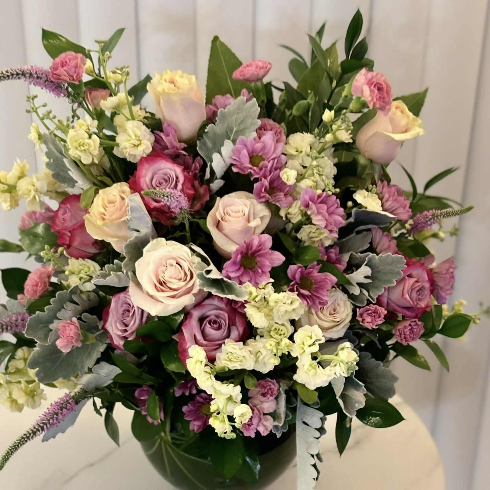 Mixed pink and cream roses in a dark glass vase