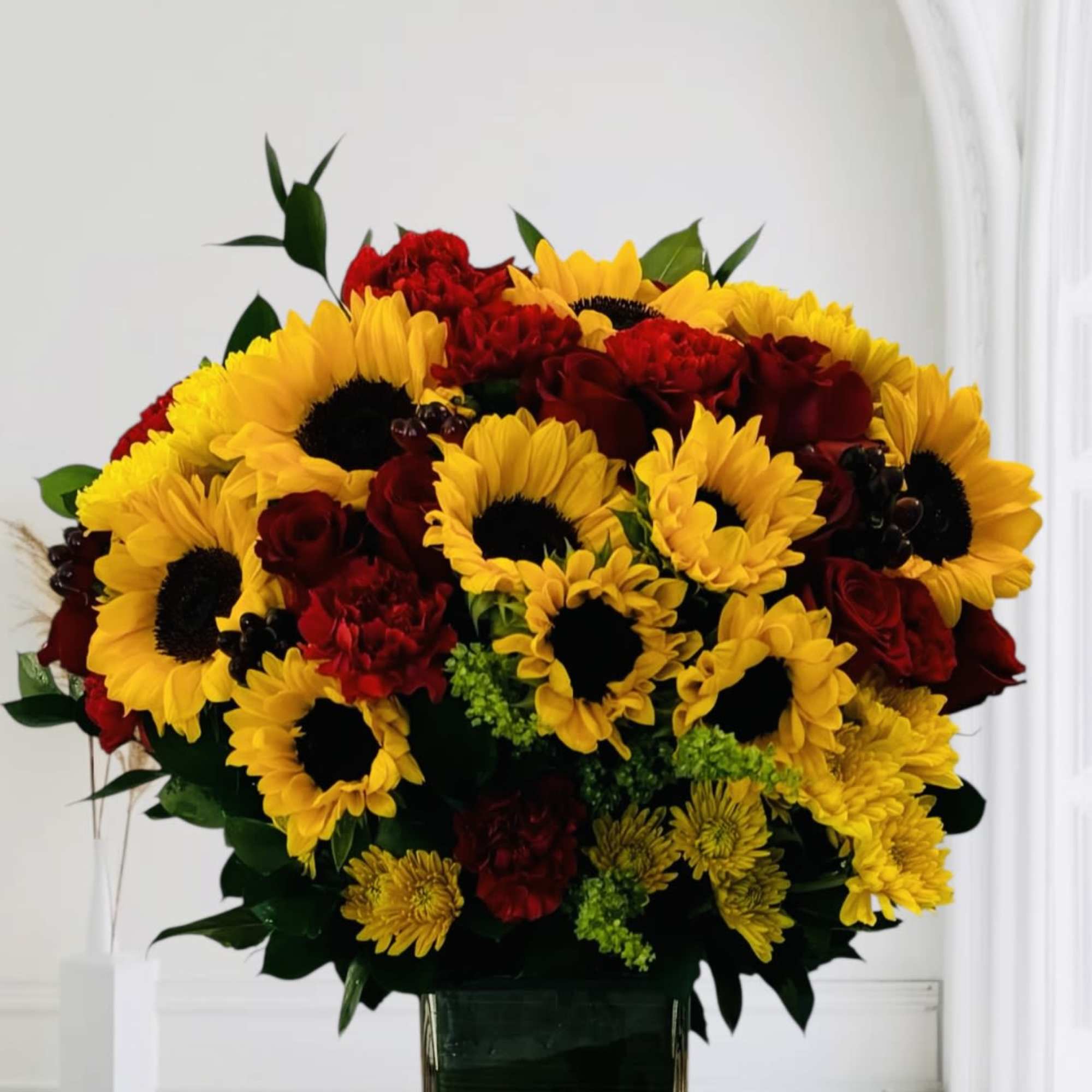 Bouquet of yellow sunflowers and red roses in a glass vase
