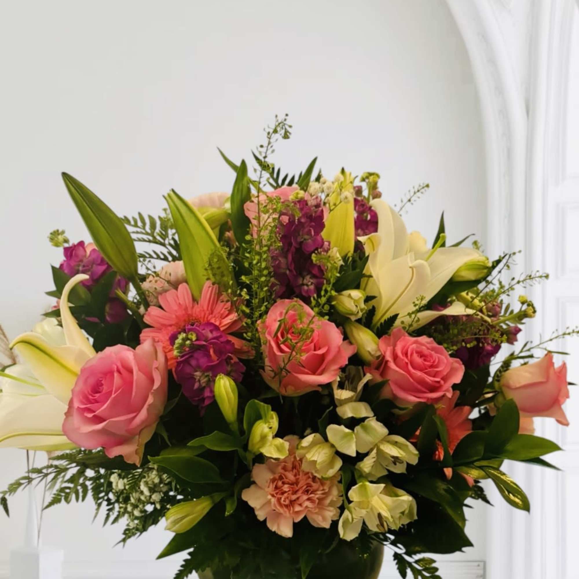 Pink roses and lilies arranged in a dark vase