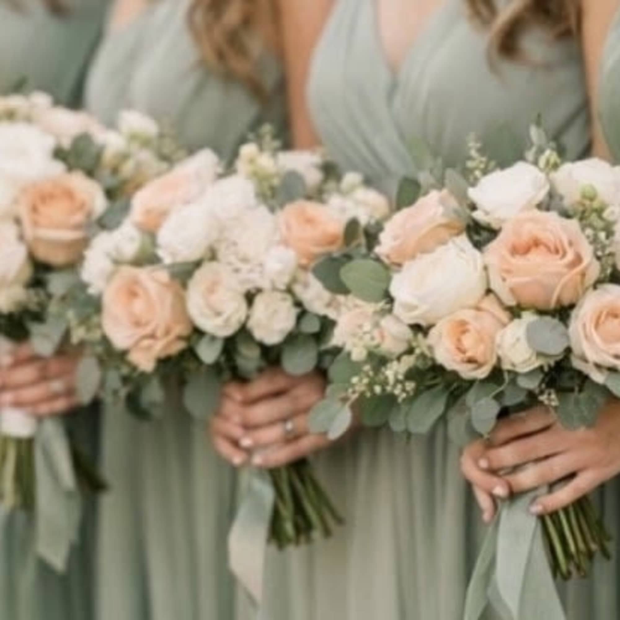 Bridesmaids holding bouquets of blush and white roses