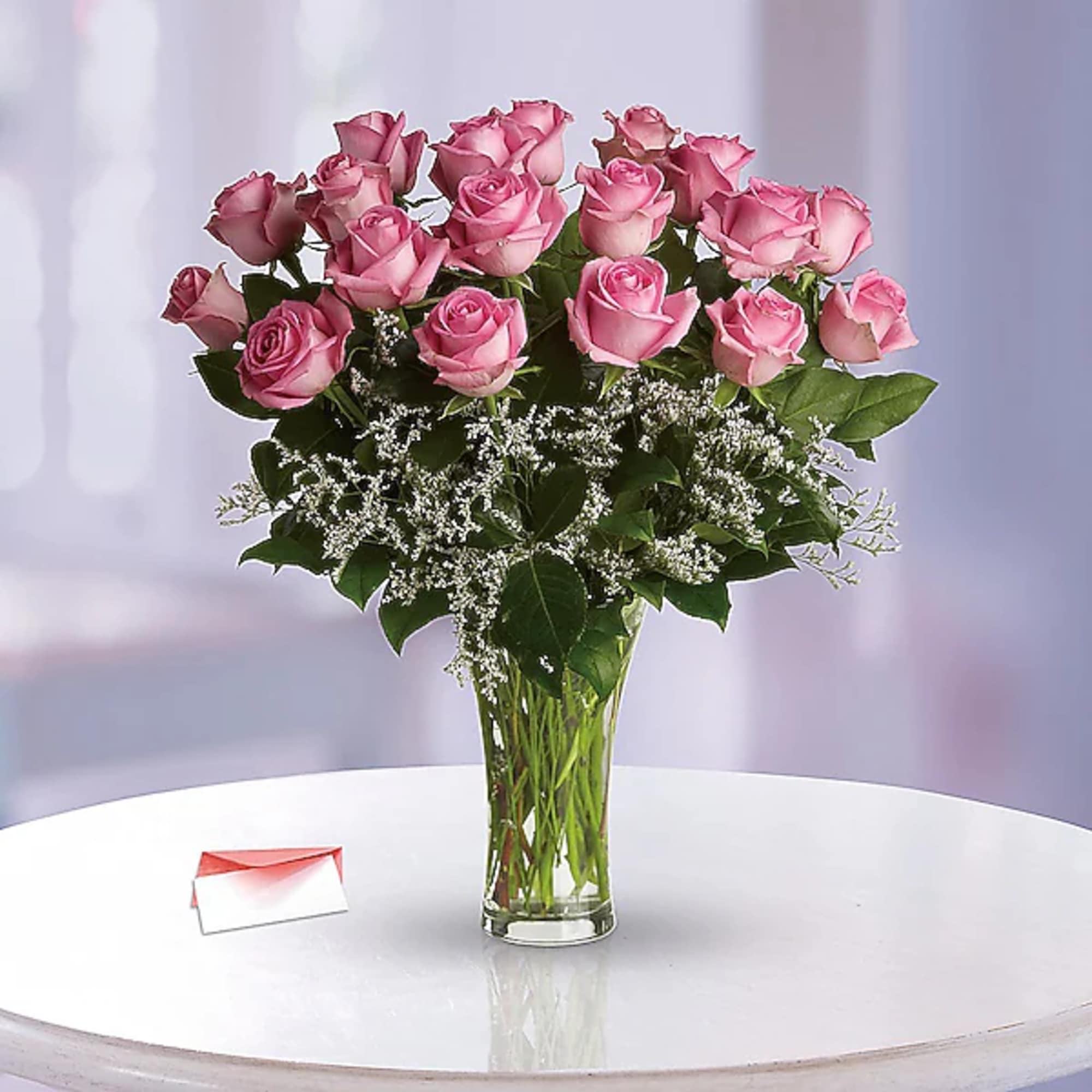 Pink roses arranged in a clear glass vase with baby's breath.