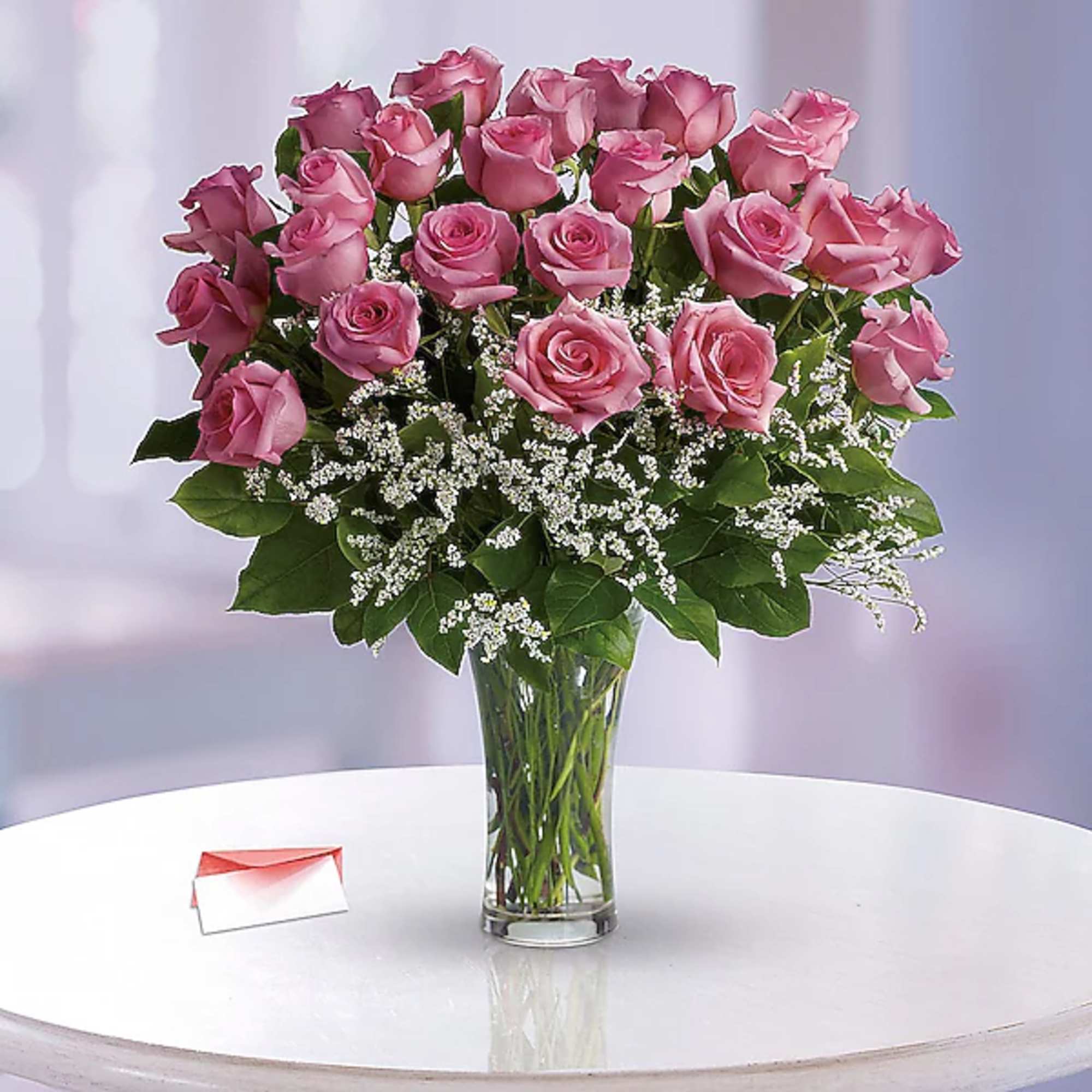 Pink roses arranged in a clear glass vase with white filler flowers.