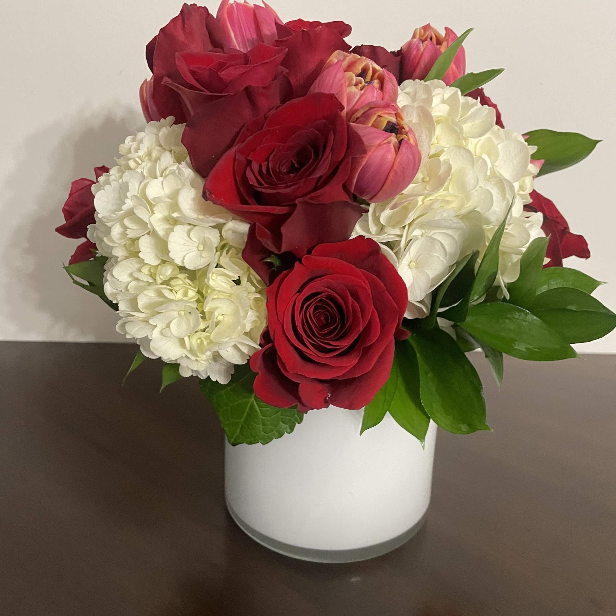 Red roses and white hydrangeas in a white vase
