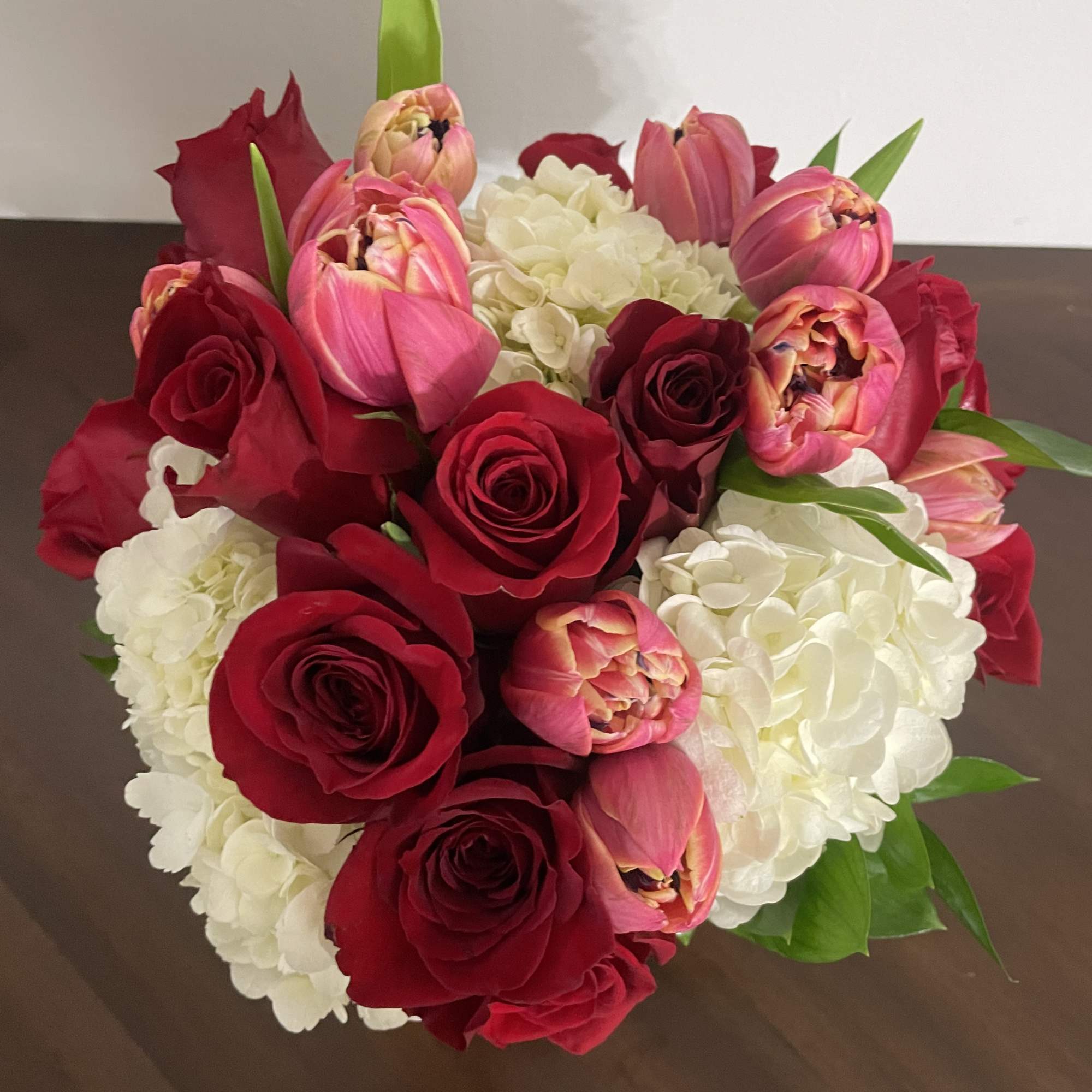 Bouquet of red roses, pink tulips, and white hydrangeas
