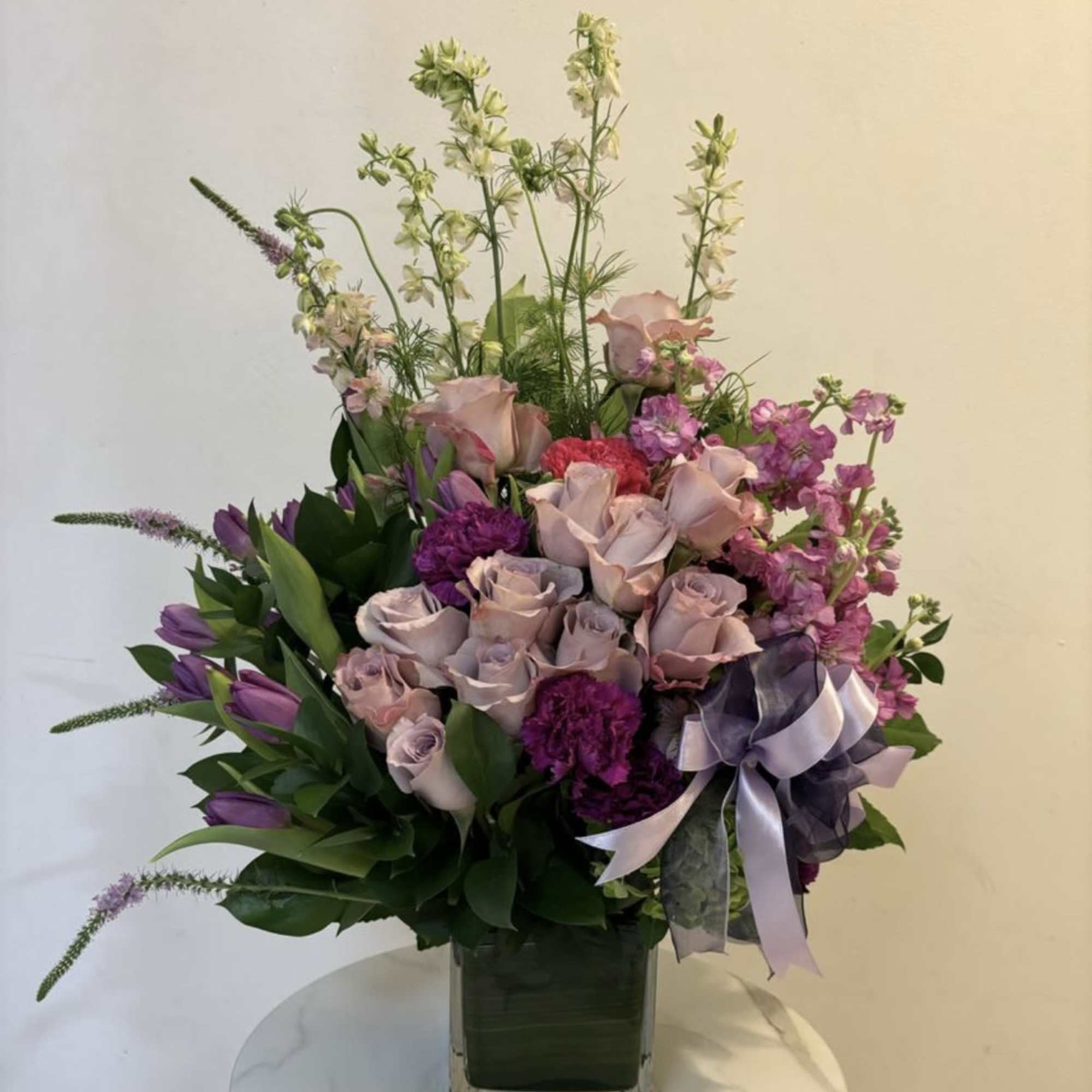 Lavender and pink floral arrangement in a square glass vase with a ribbon
