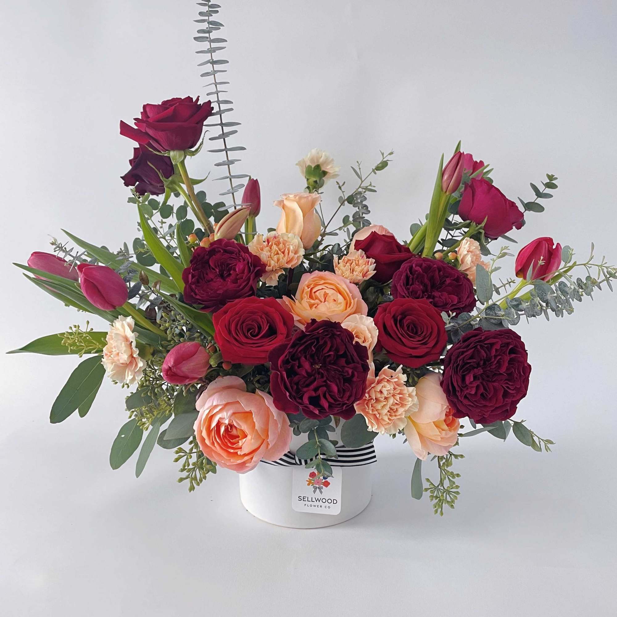 Bouquet of red, pink, and peach roses in a white hat box