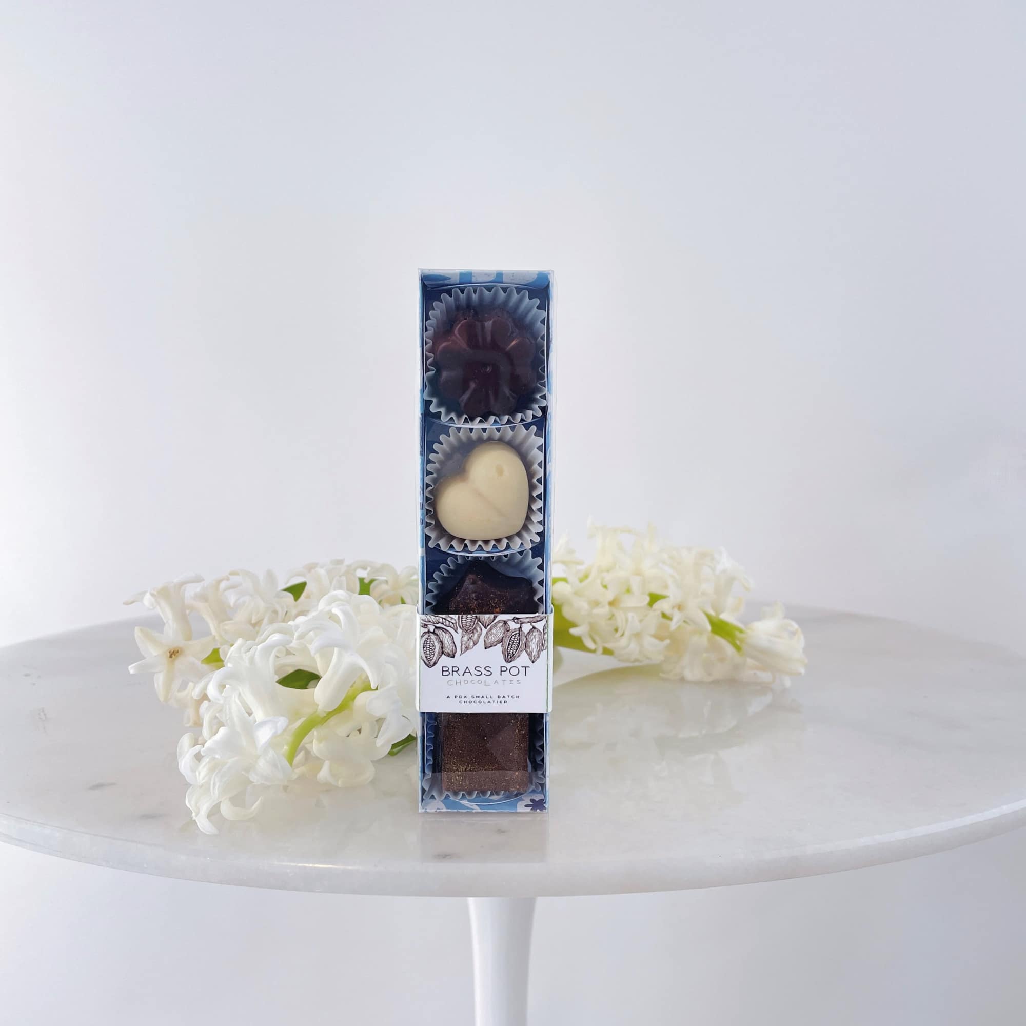 Box of chocolates with white flowers on a table