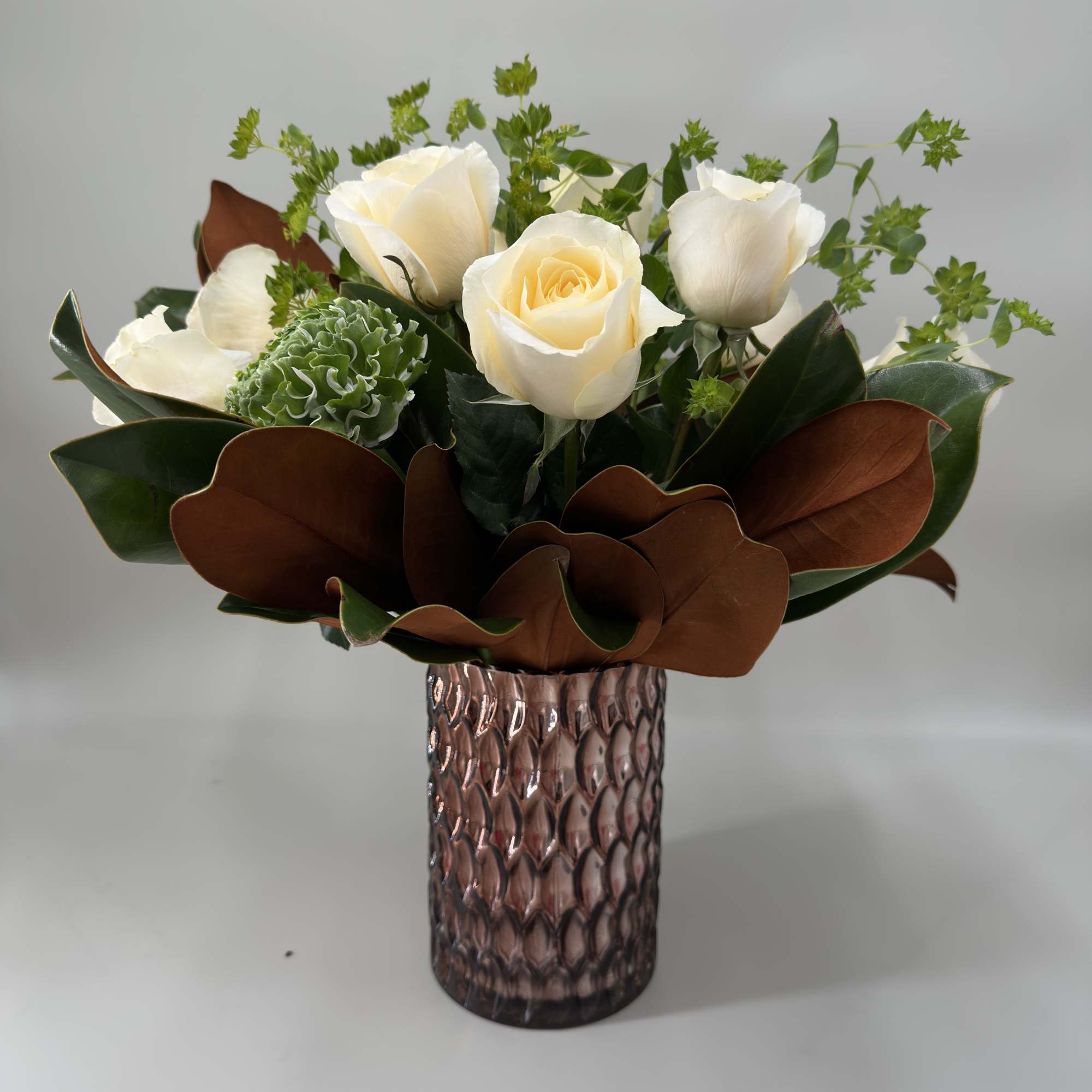 White roses and green blooms in a textured glass vase