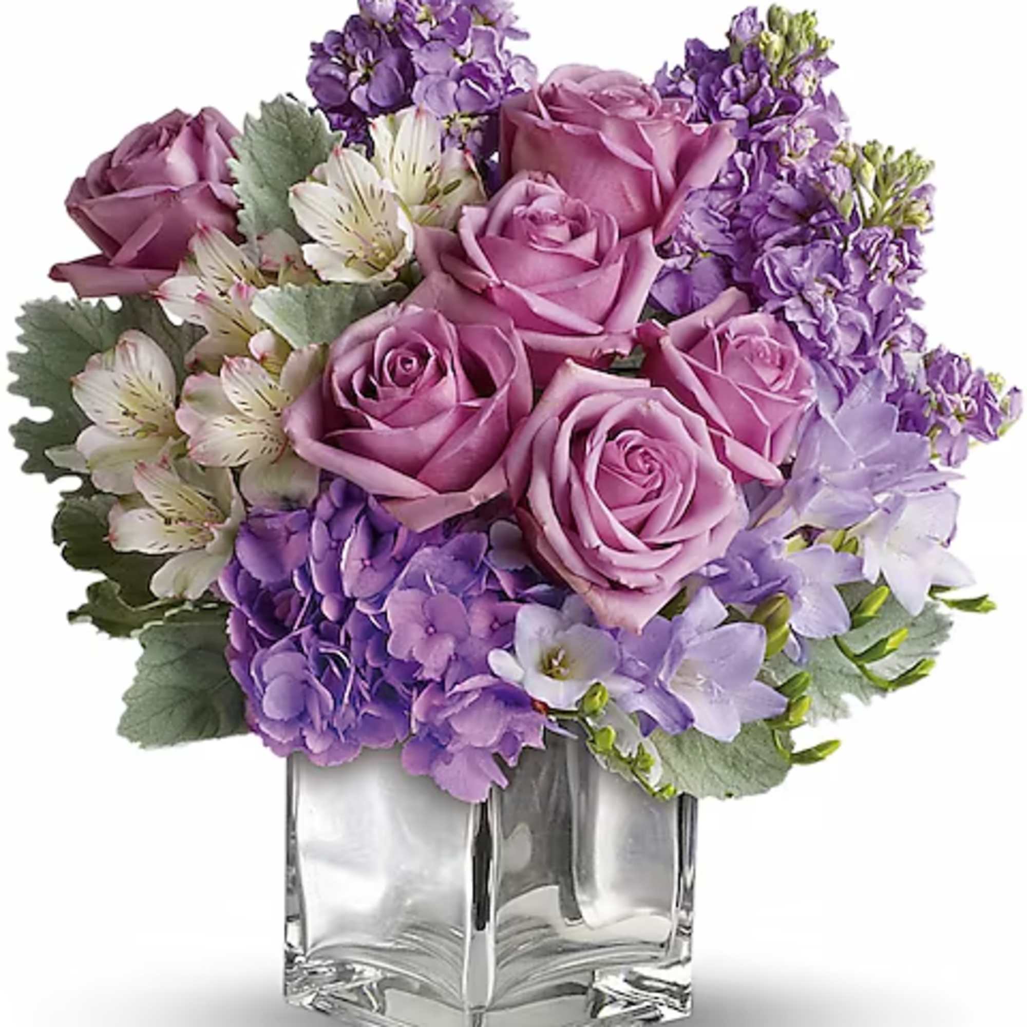 Lavender roses and purple flowers arranged in a clear glass vase