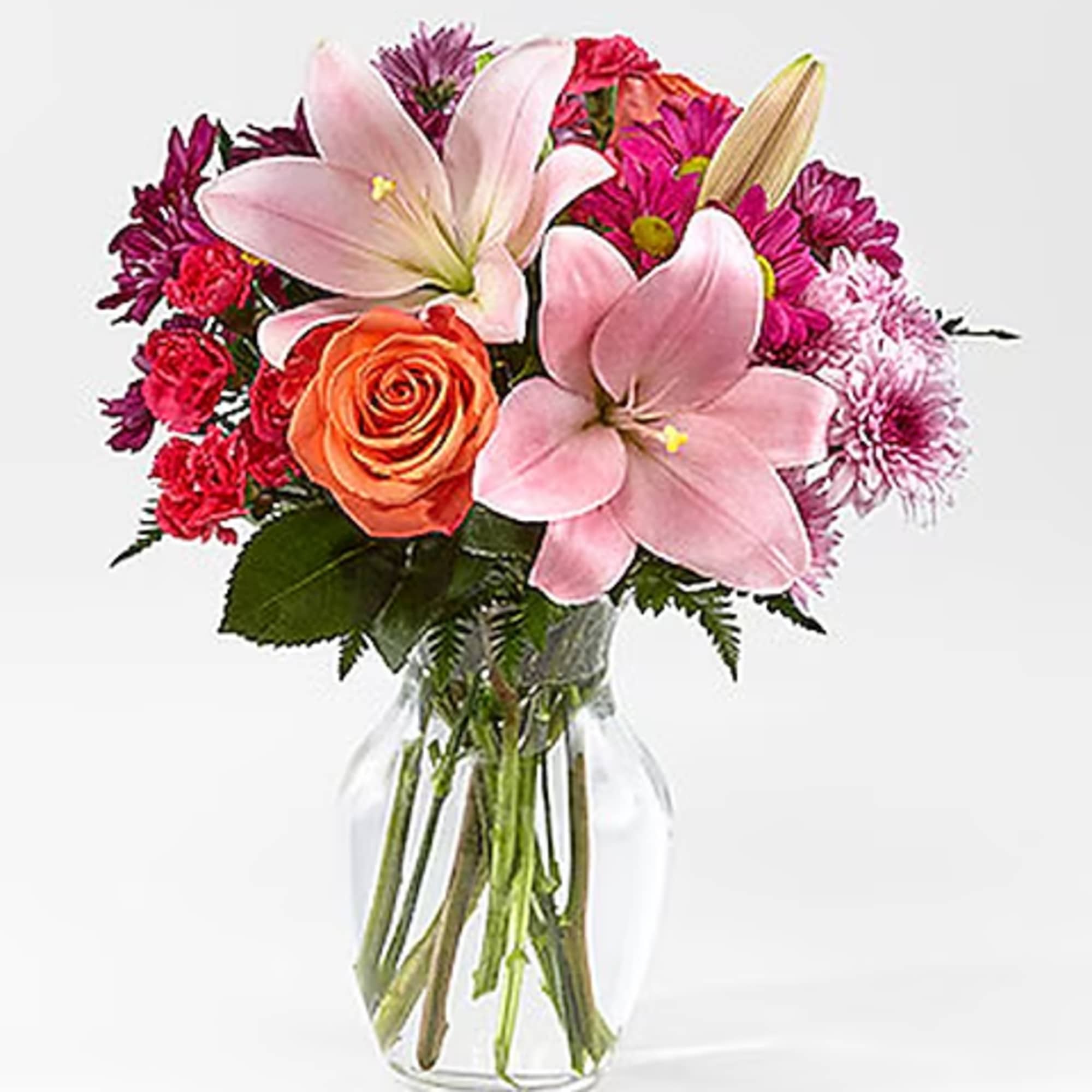 Pink lilies and mixed roses in a clear glass vase