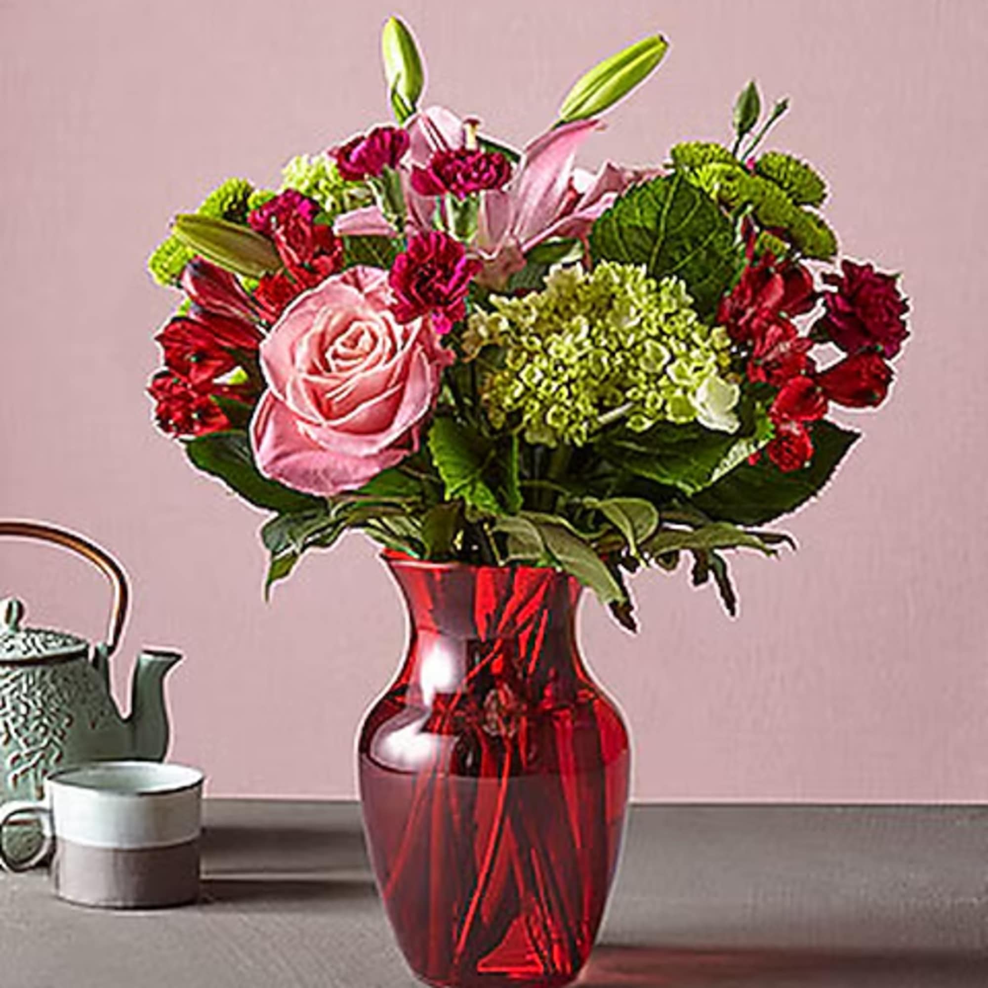 Pink and red flower arrangement in a red glass vase