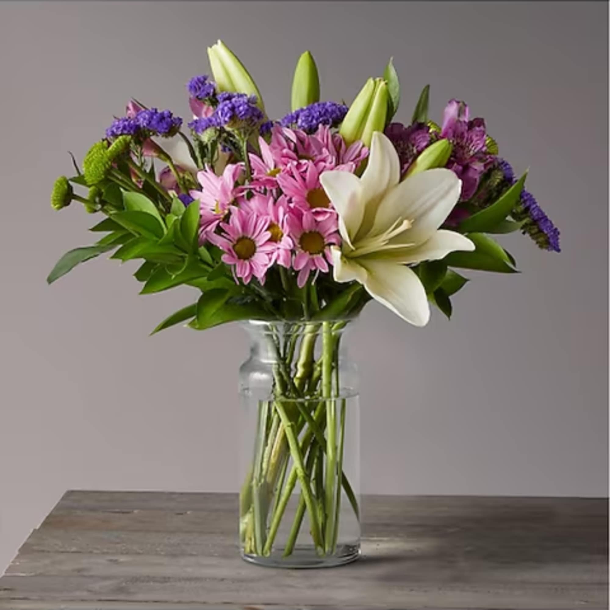 Bouquet of pink daisies and white lilies in a clear glass vase