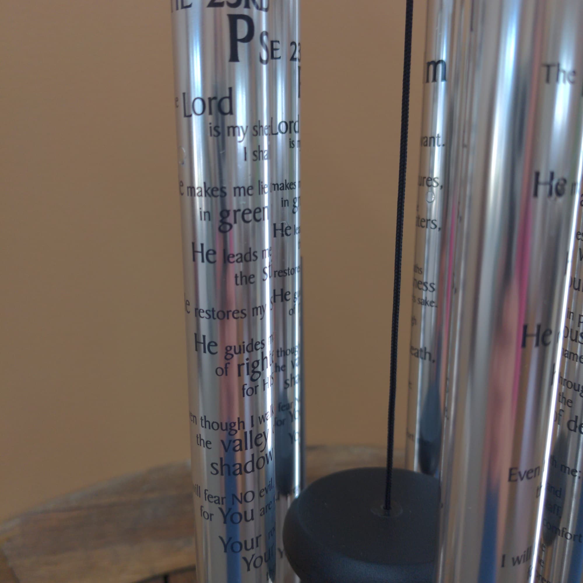 Silver wind chimes with printed Bible verses hanging indoors