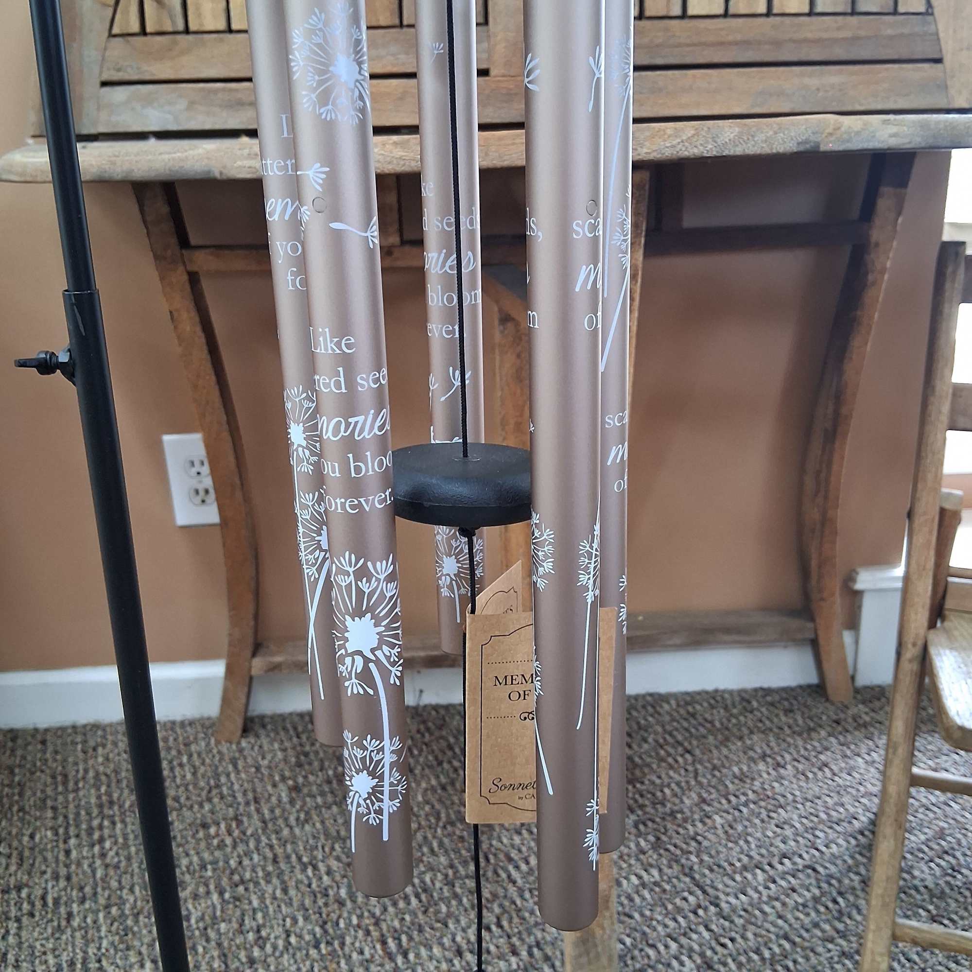 A hanging memorial wind chime with engraved tubes and a black striker.