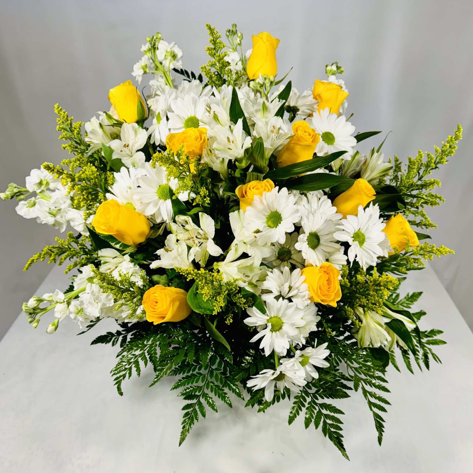 Yellow roses and white daisies in a low floral arrangement