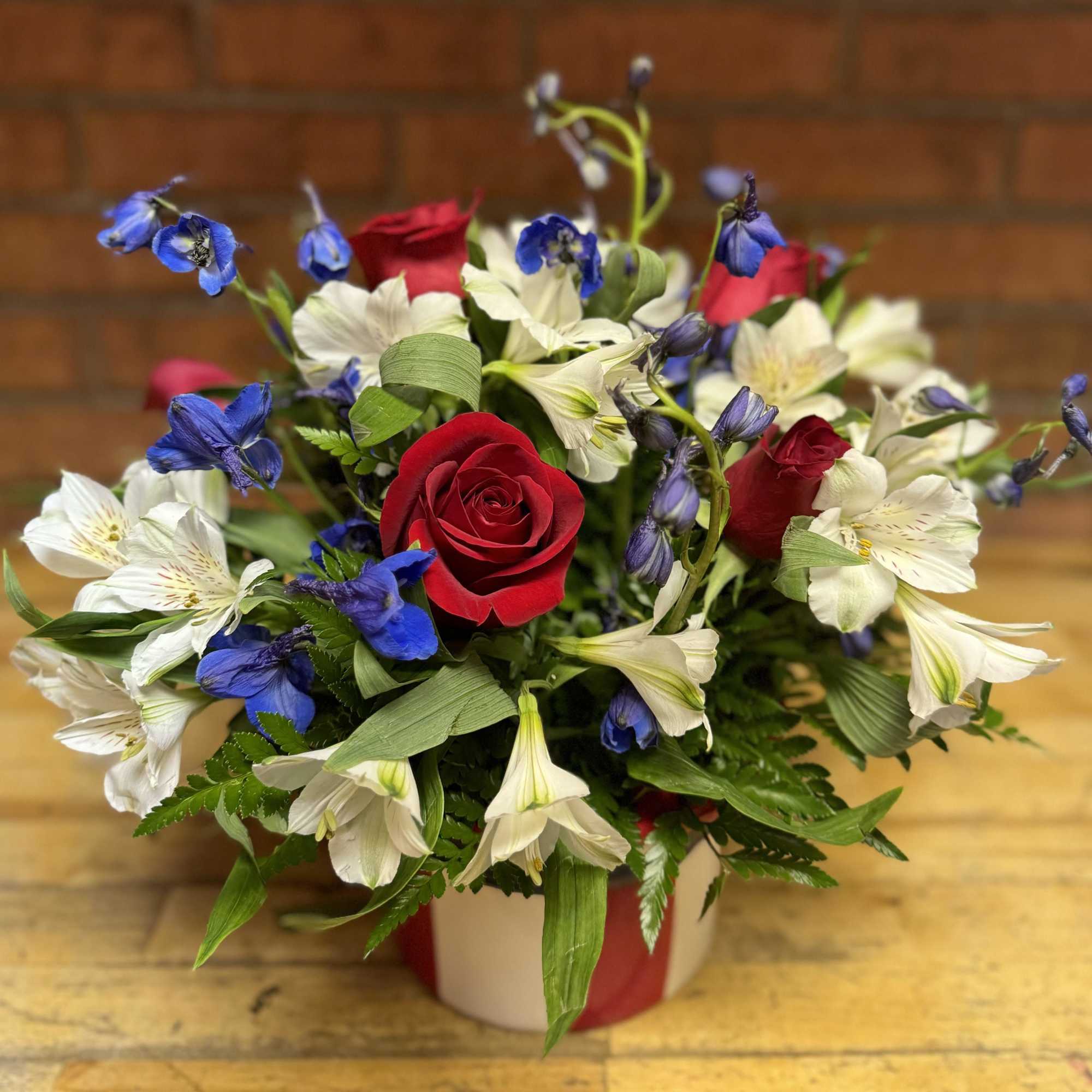 Red roses and white-blue alstroemeria in a wrapped vase arrangement