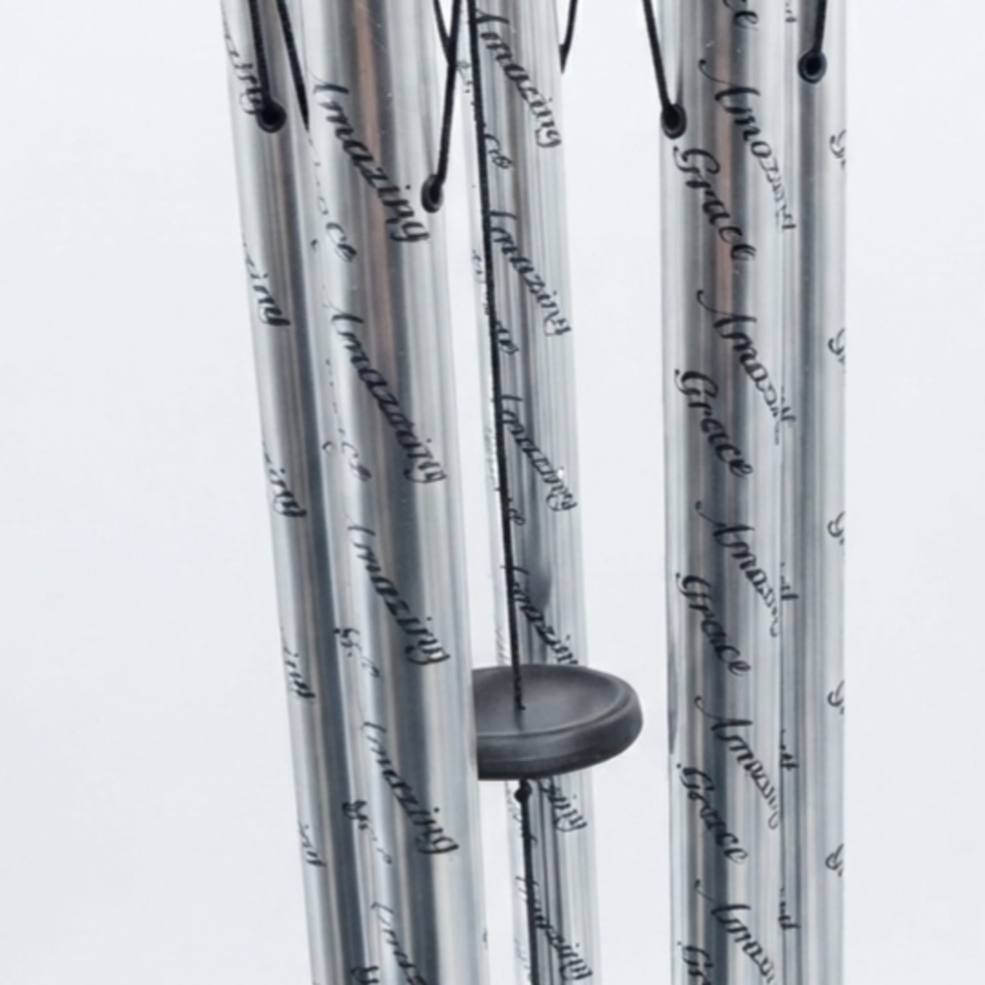 Silver metal wind chime with black cords and a round striker