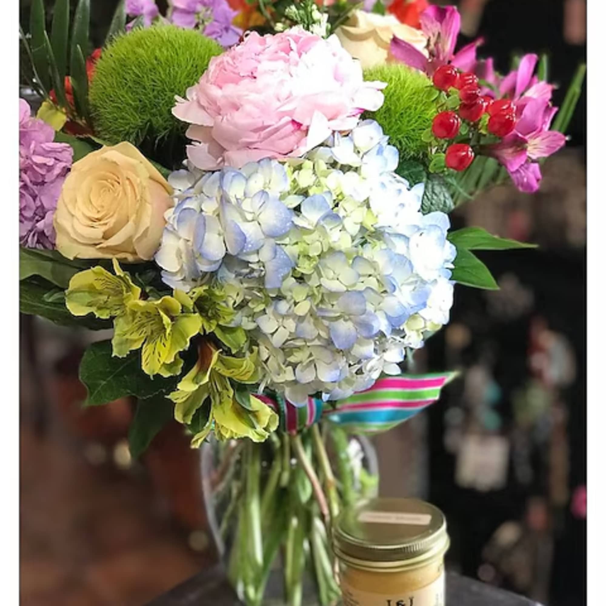Mixed bouquet in a glass vase with a candle beside it