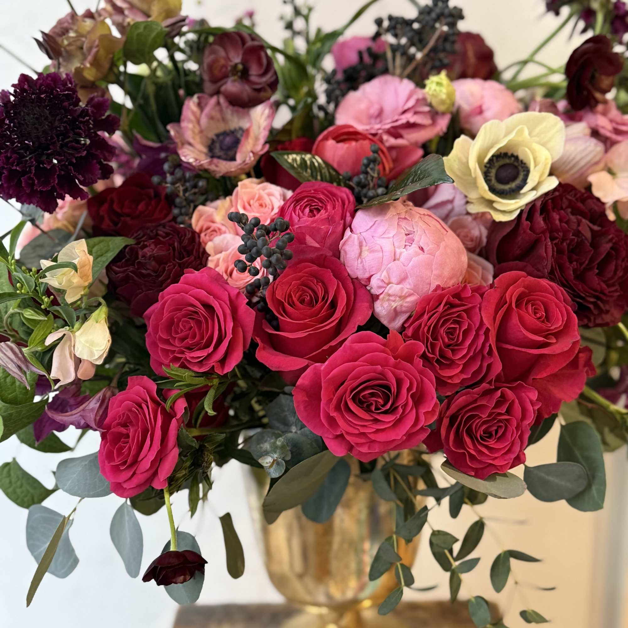 Bouquet of hot pink and burgundy roses in a gold vase