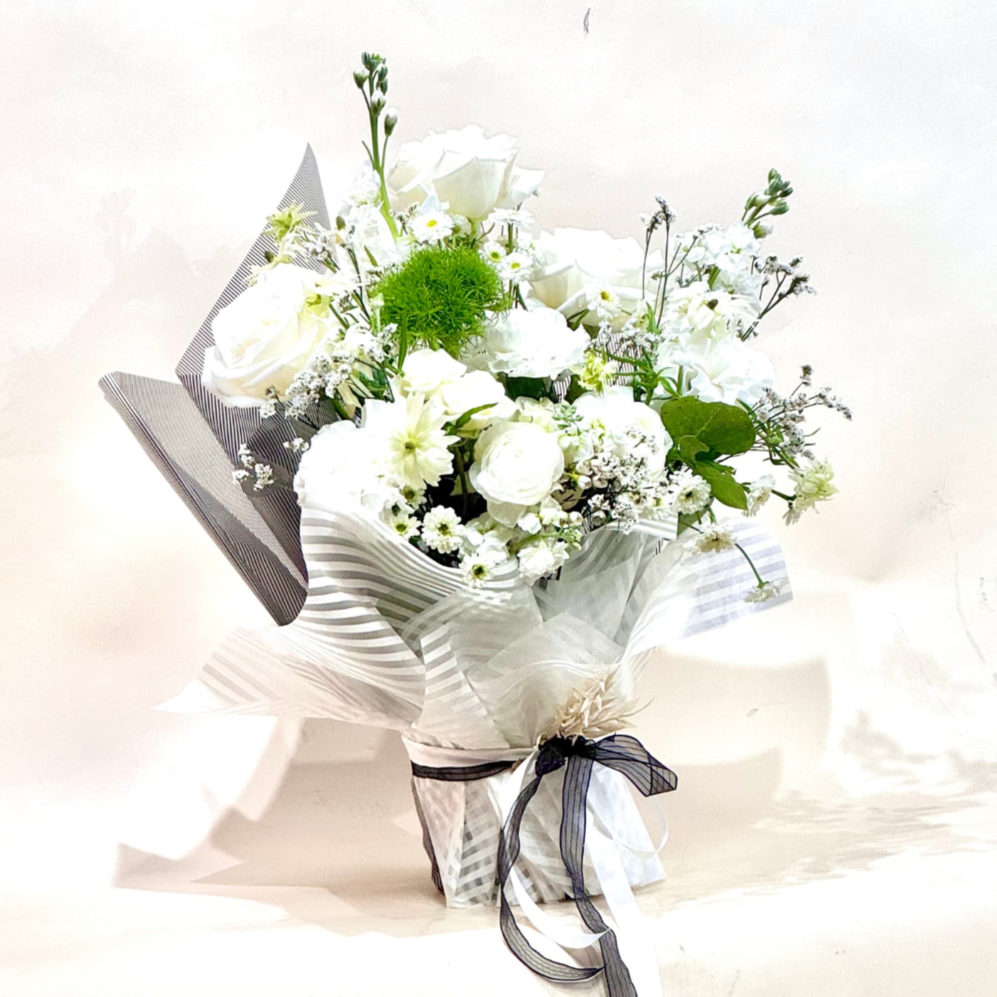 White bouquet with roses and small daisies wrapped in striped paper, photo 2 of 3