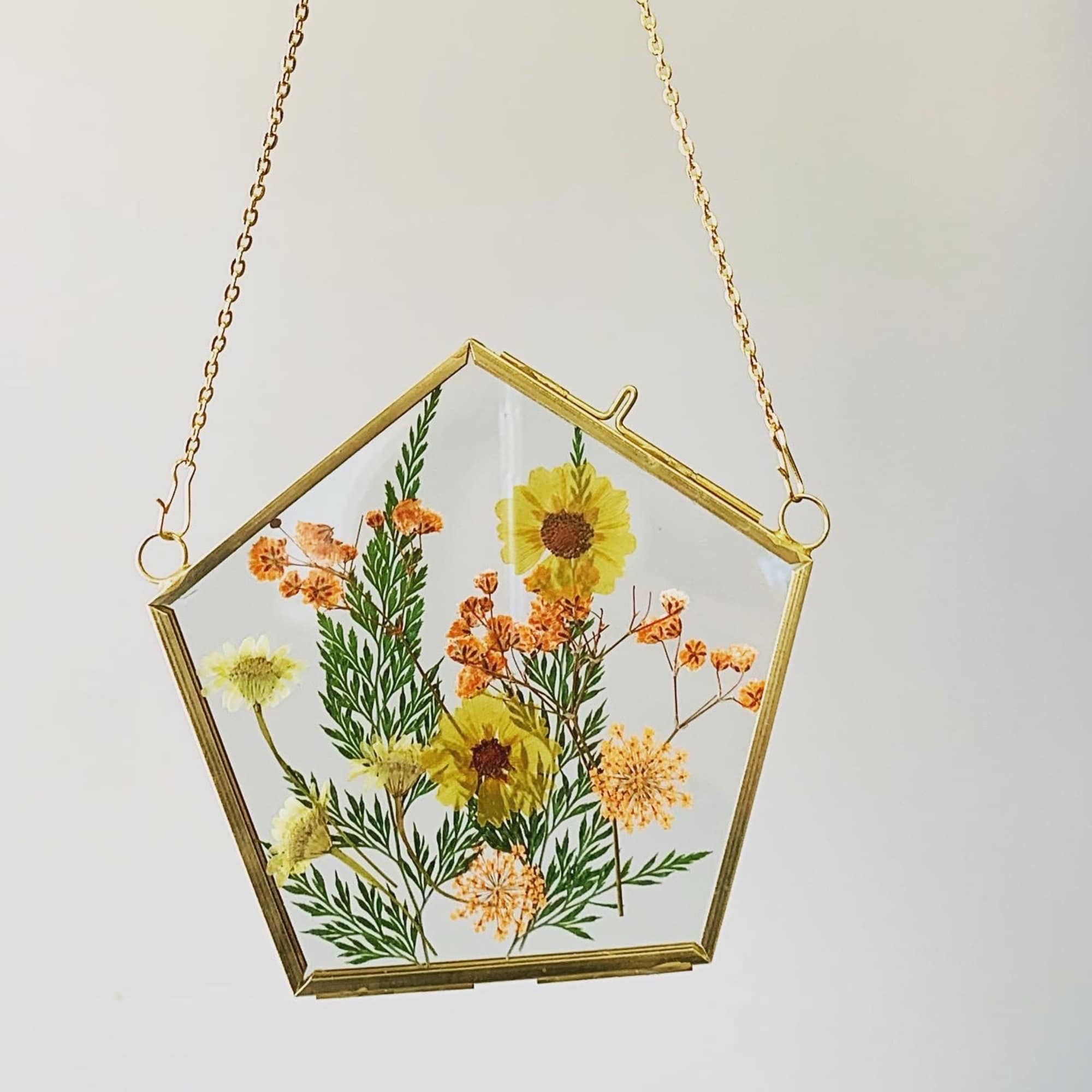 Pentagon-shaped hanging glass frame with pressed yellow and orange flowers