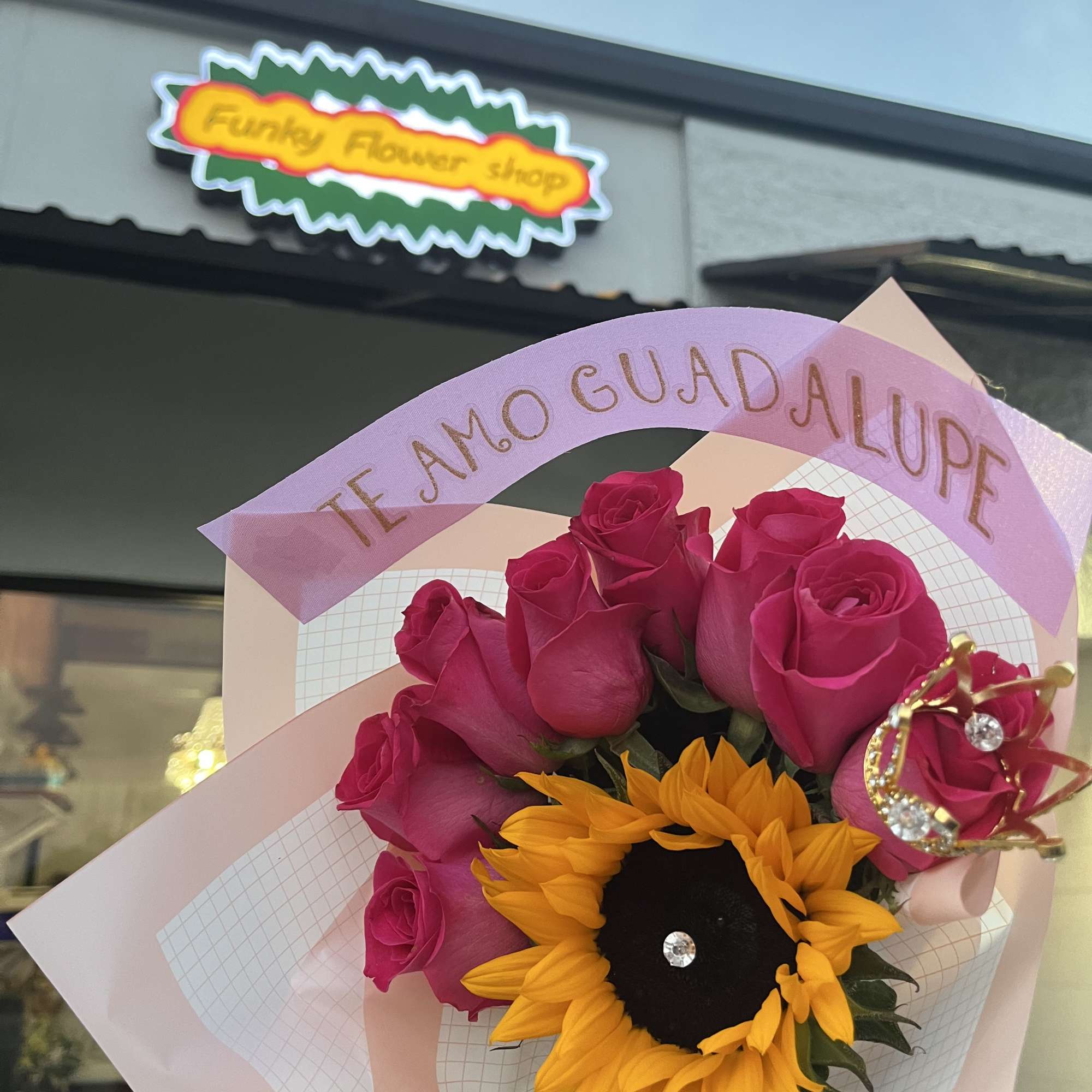 Bouquet of pink roses and a sunflower with a pink ribbon