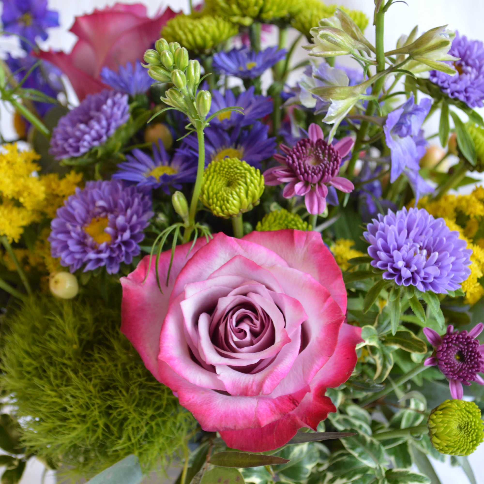 Close-up bouquet with a pink rose and purple flowers
