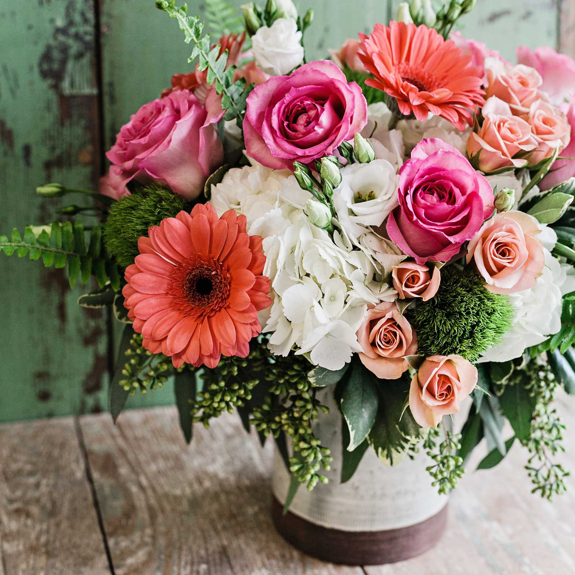 Pink and peach roses with orange gerbera daisies in a vase