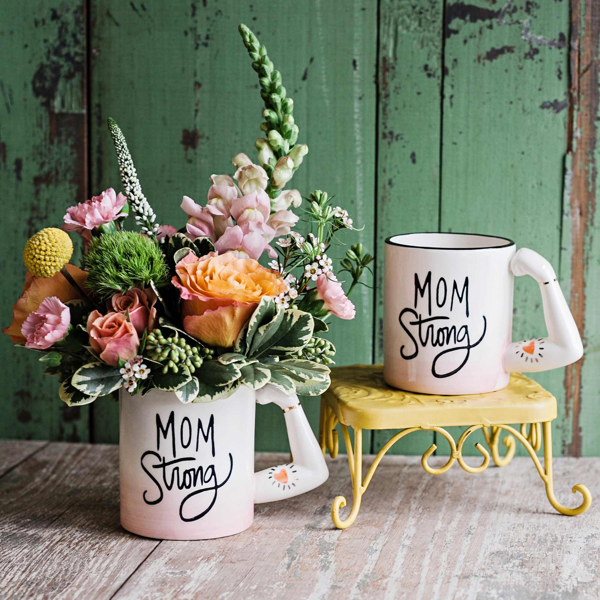 Floral arrangement in a mug with a matching "Mom Strong" mug beside it