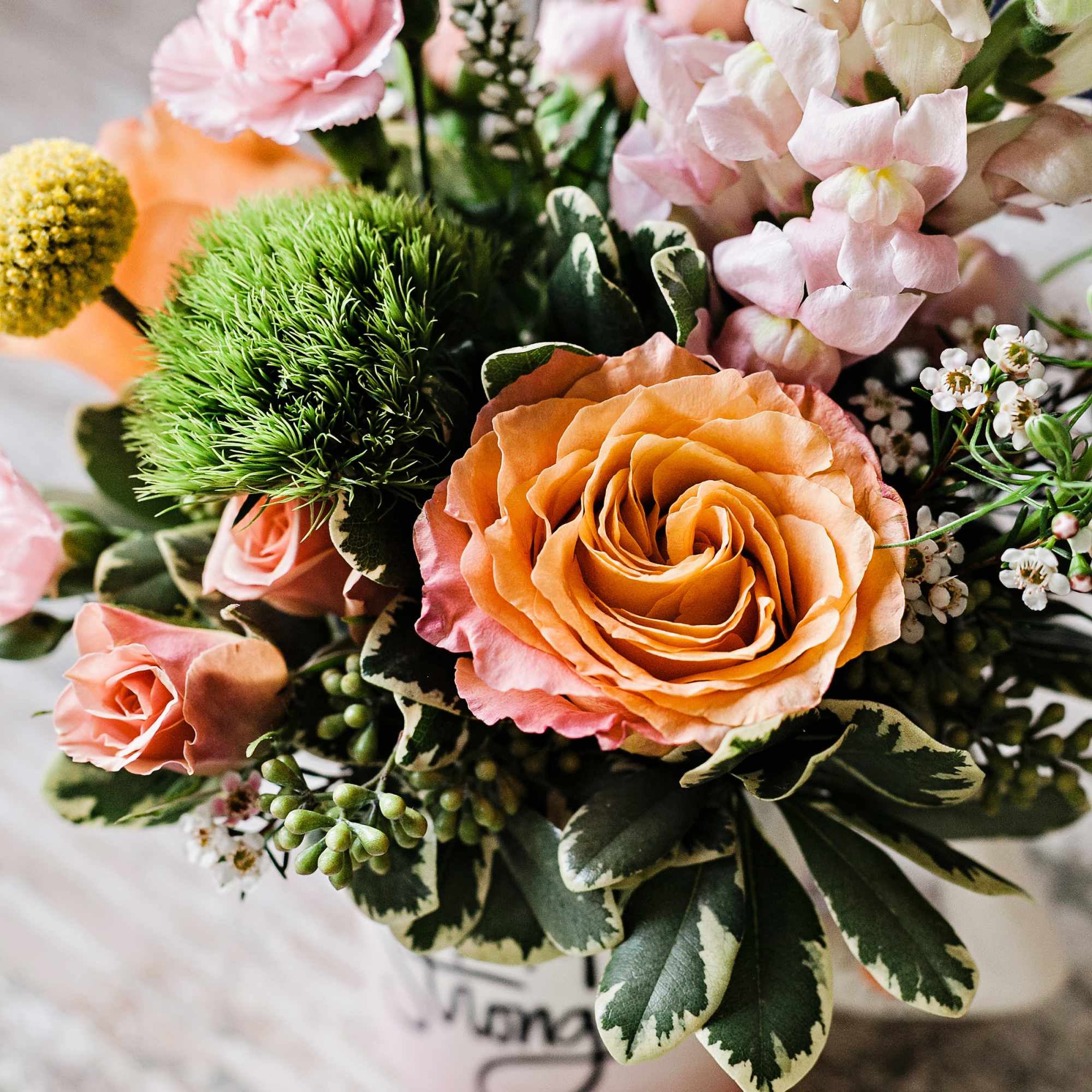 Bouquet of peach and pink roses with pale snapdragons in a vase