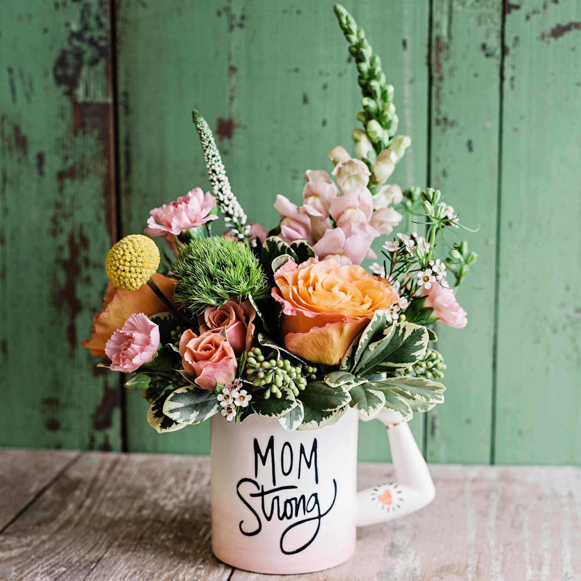 Bouquet of mixed flowers in a white mug that says Mom Strong