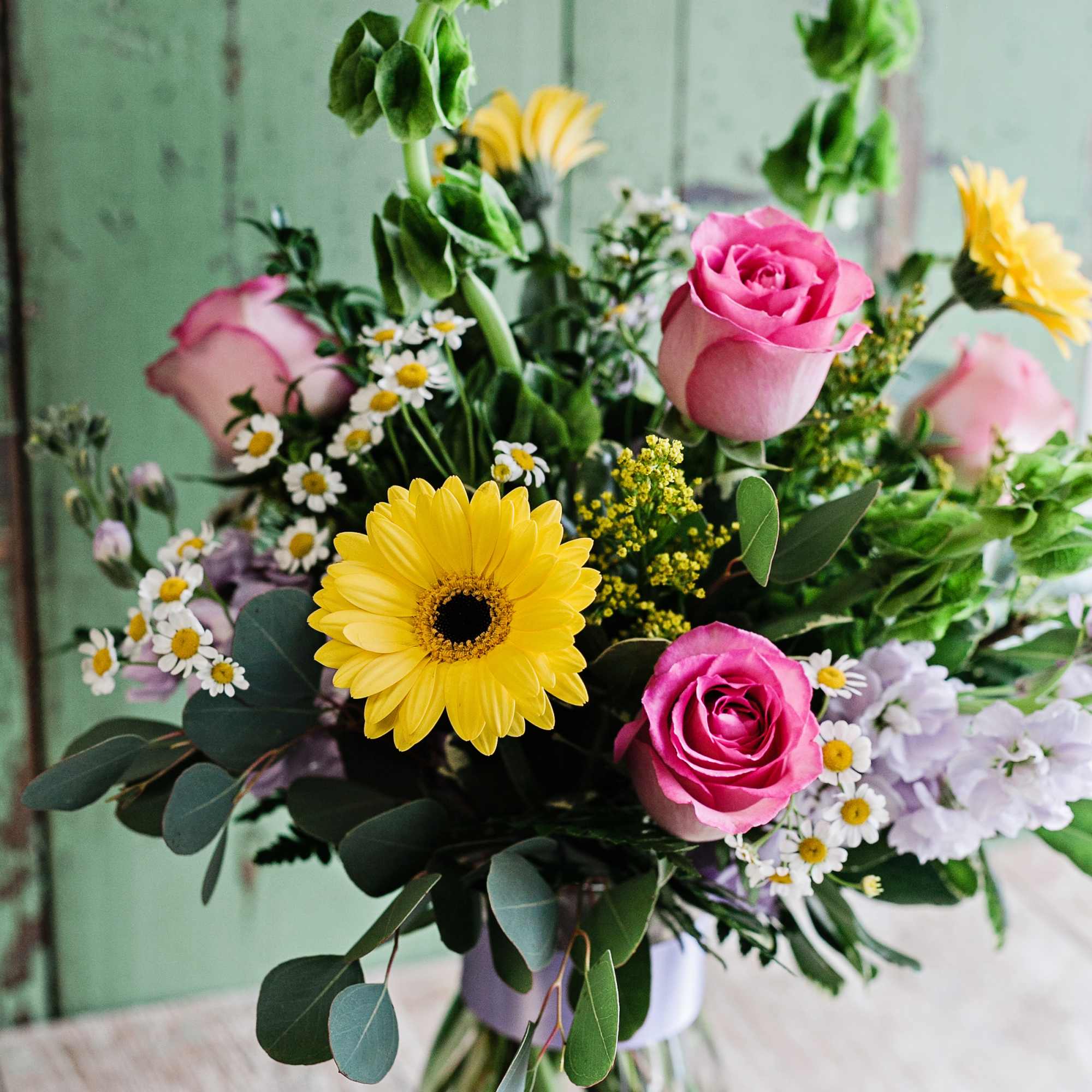 Bouquet of pink roses, yellow gerbera daisies, and small white daisies